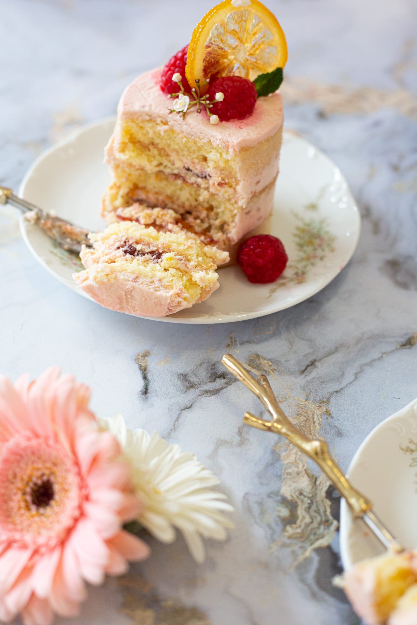 A cut raspberry and lemon mini cake with a forkful on the plate, from slightly above