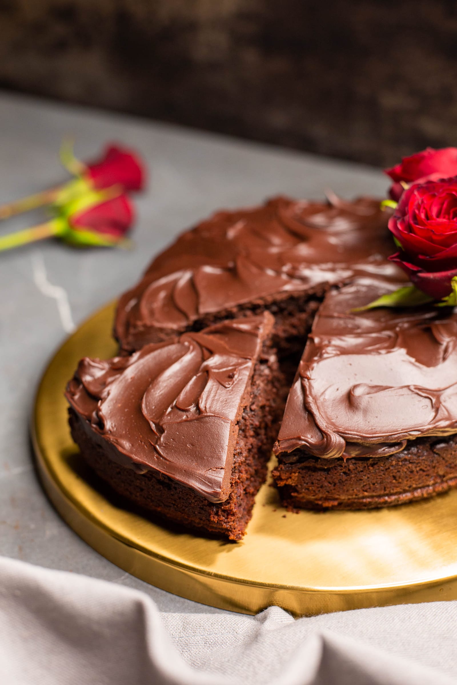 A chocolate and beetroot cake with a wedge cut out, red roses on top