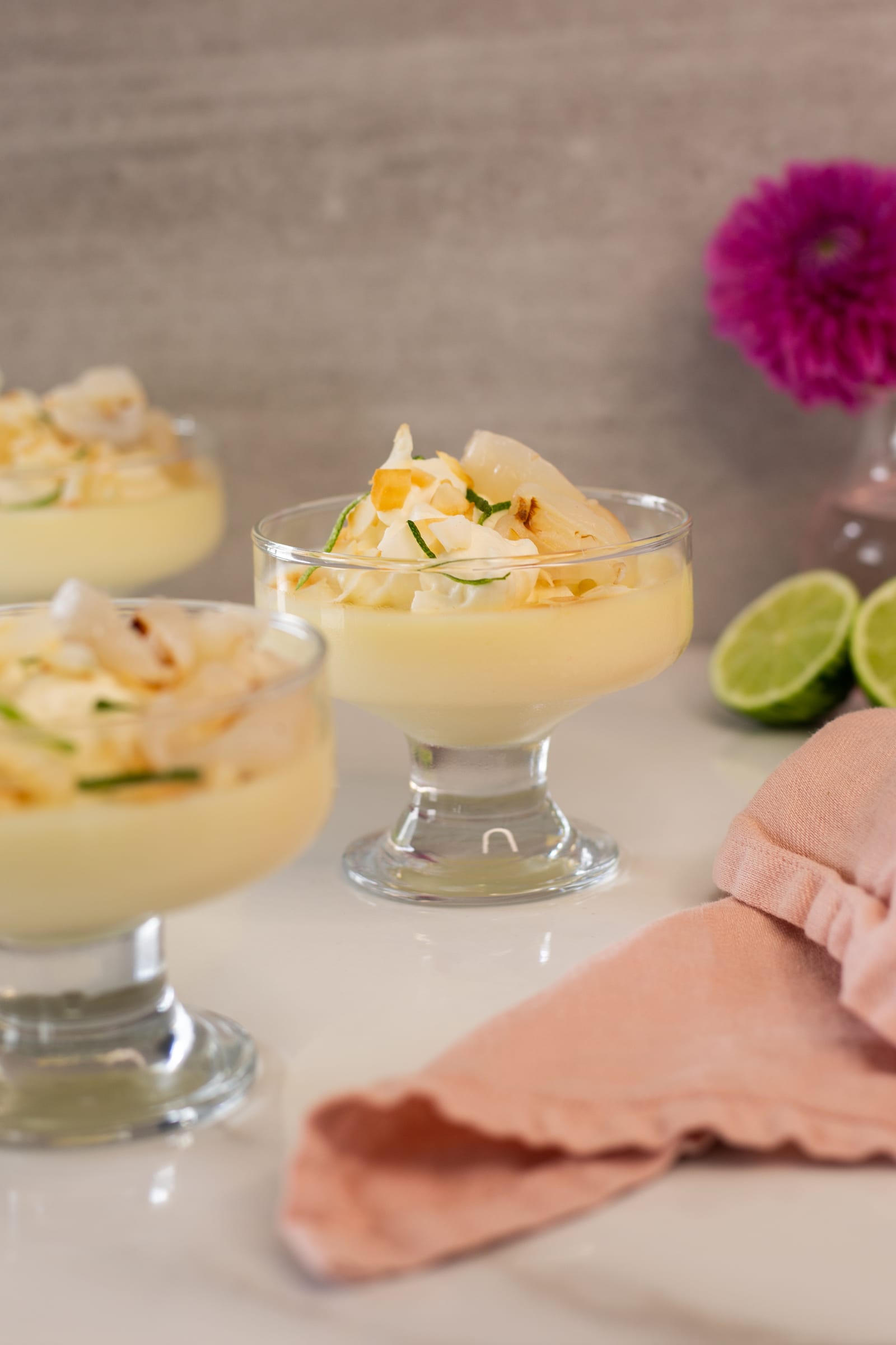 A low view across a row of lime and coconut possets with litchis and halved limes