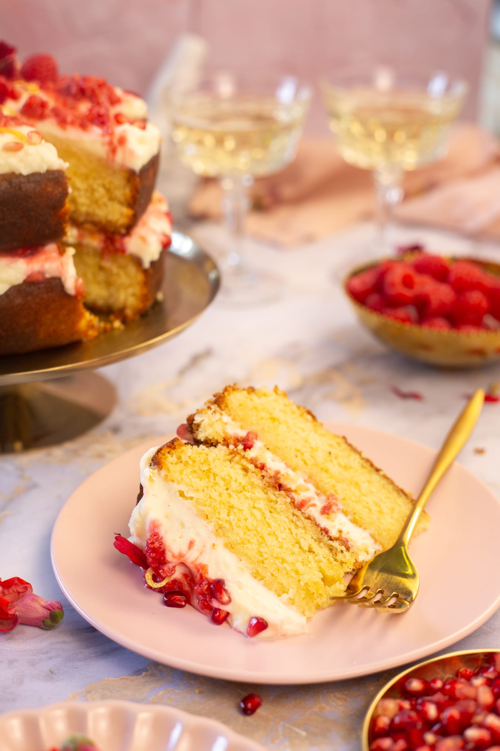 A slice of lemon, rose and raspberry cake on a pink plate