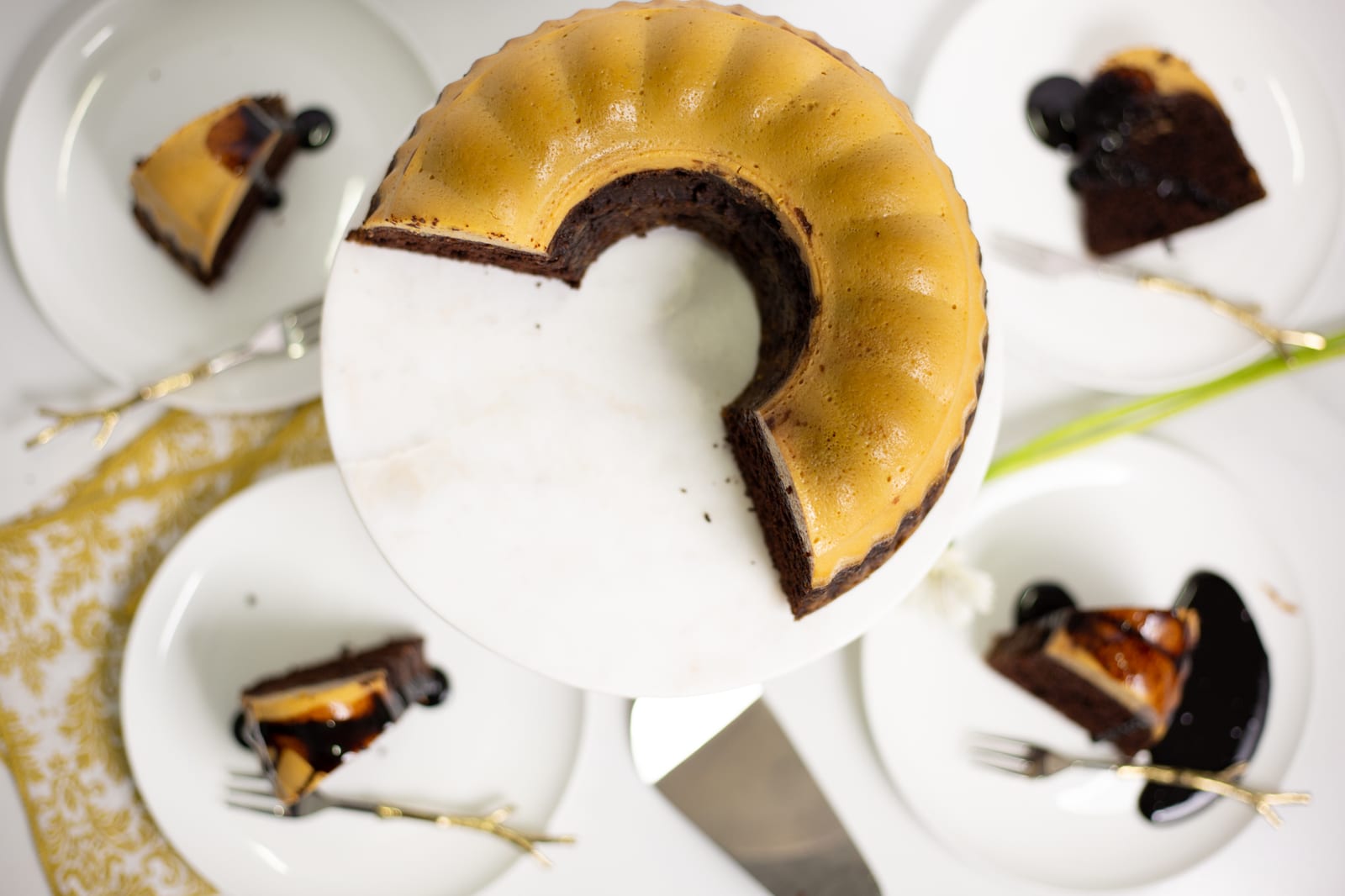 A cut caramel white chocoflan with slices on plates around it, showing the flan and chocolate cake layers, from above