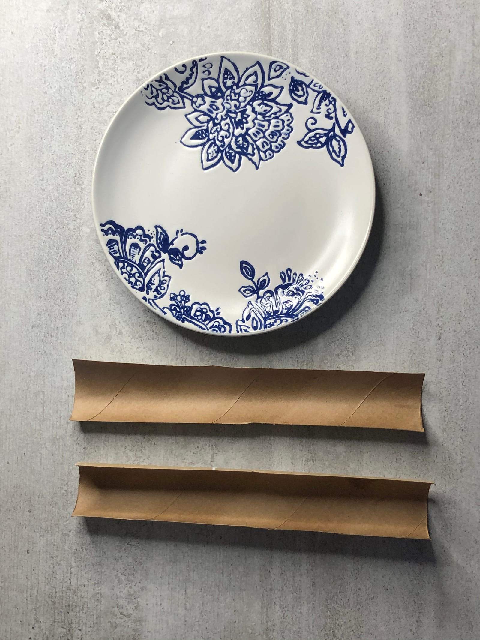 Two halved paper towel holders laid below a blue-and-white side plate, ready for shaping the chocolate petals