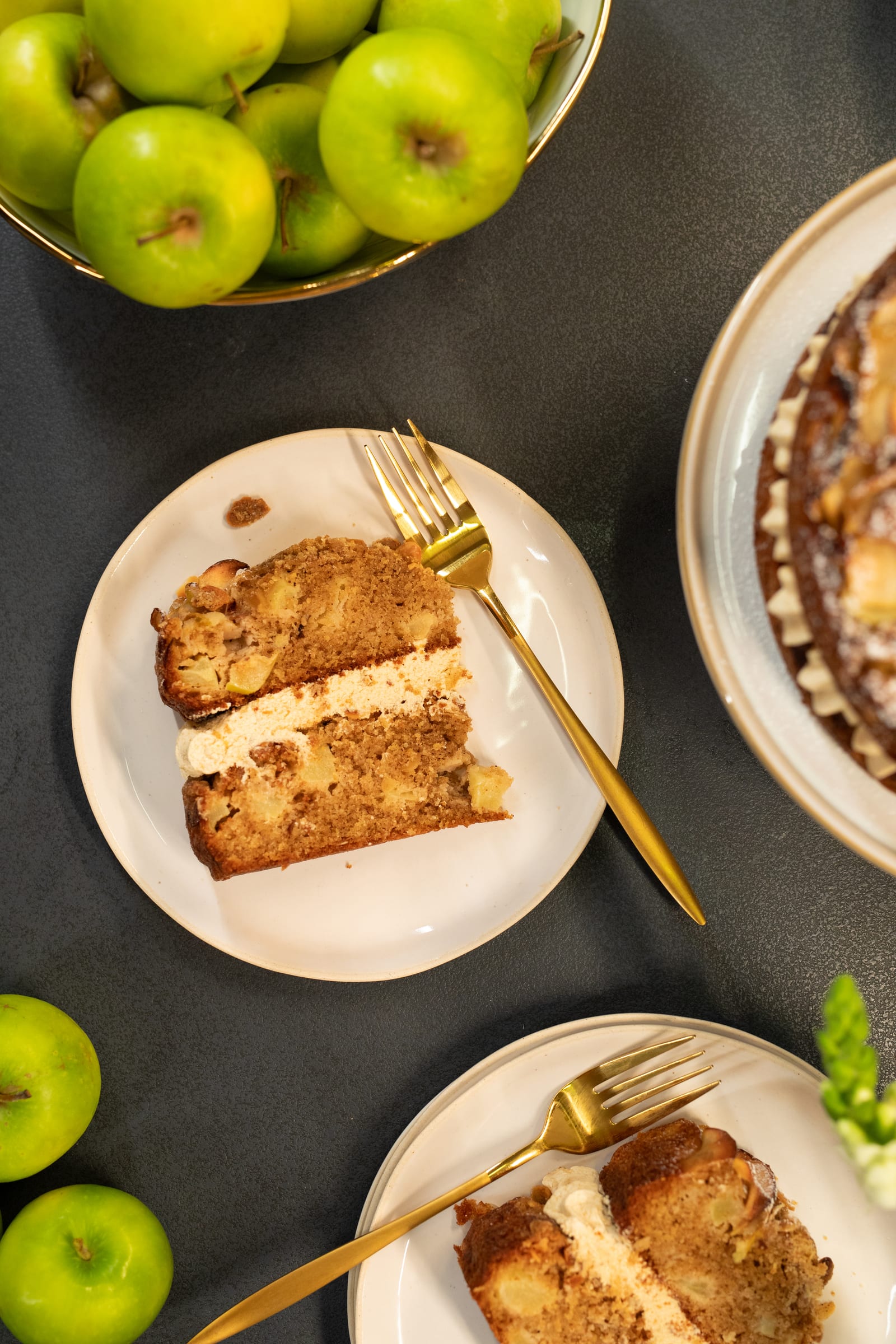 Slices of apple crumble cake on plates with gold forks, from above