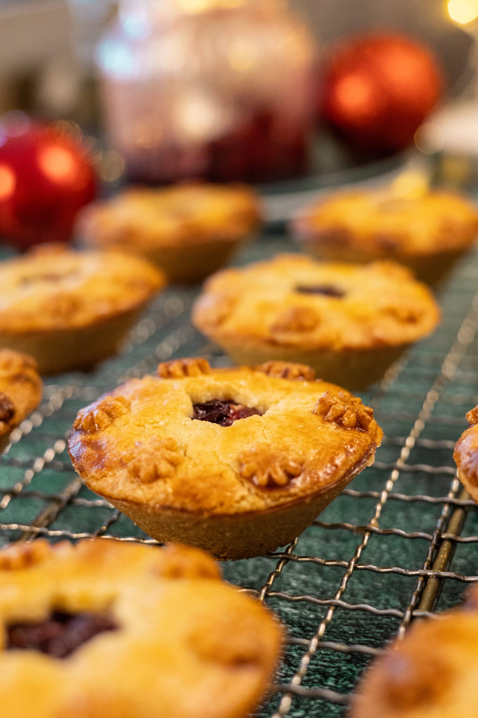 Baked pies on a wire rack, with baubles behind