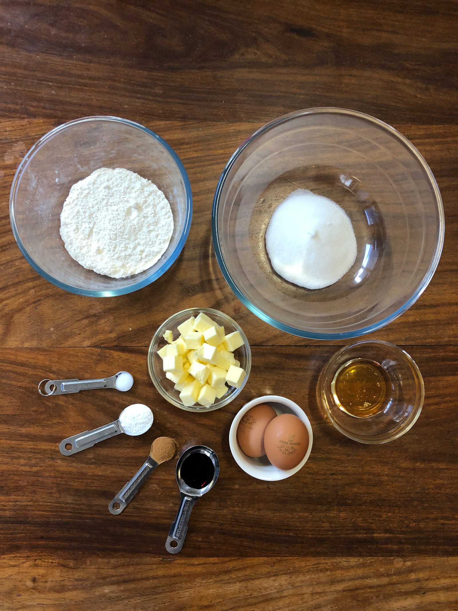 The ingredients for brown butter and almond madeleines on a wooden table, from above