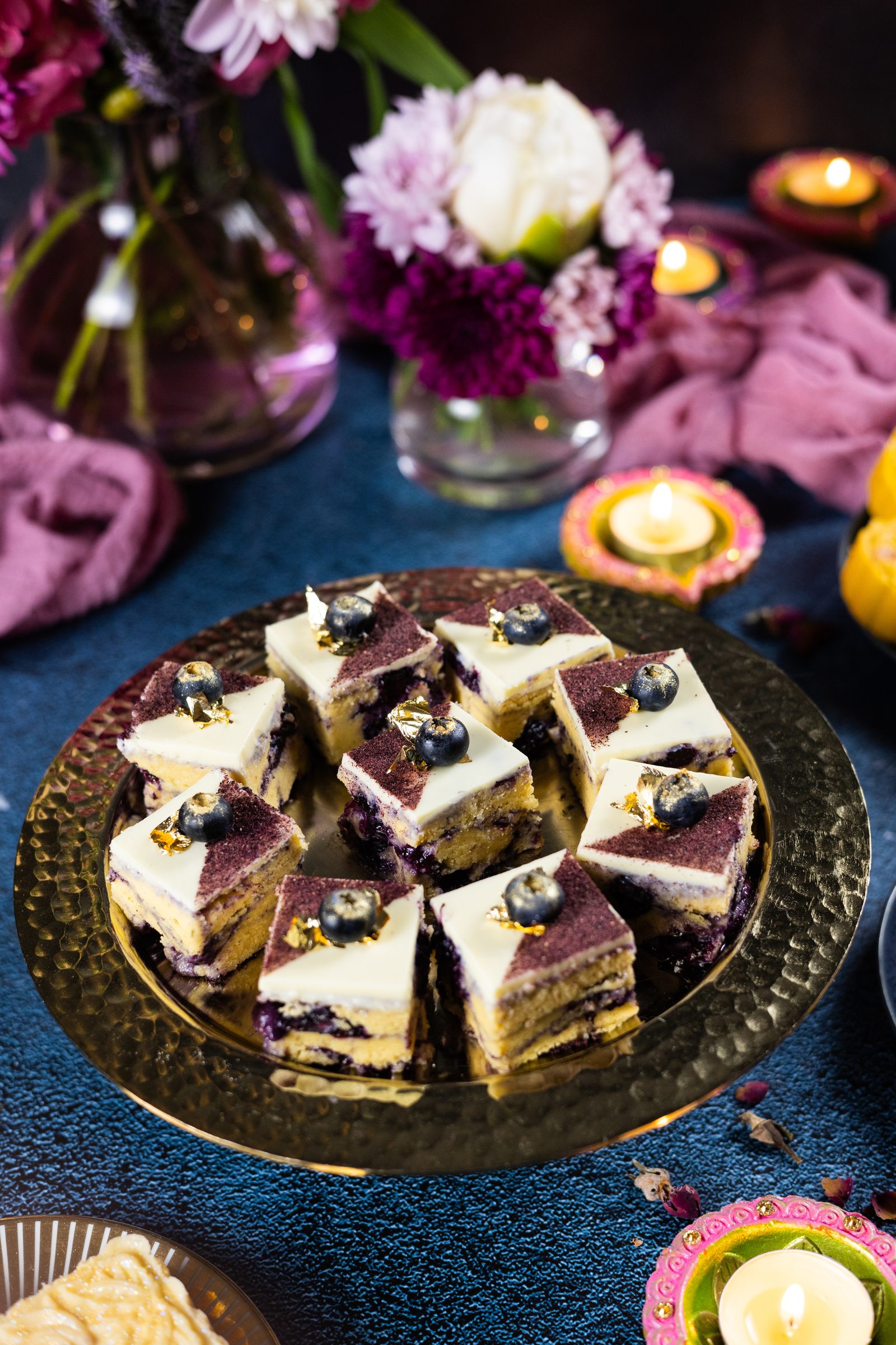 Blueberry ripple burfee squares on a gold plate at an angle, showing the purple ripple through each piece