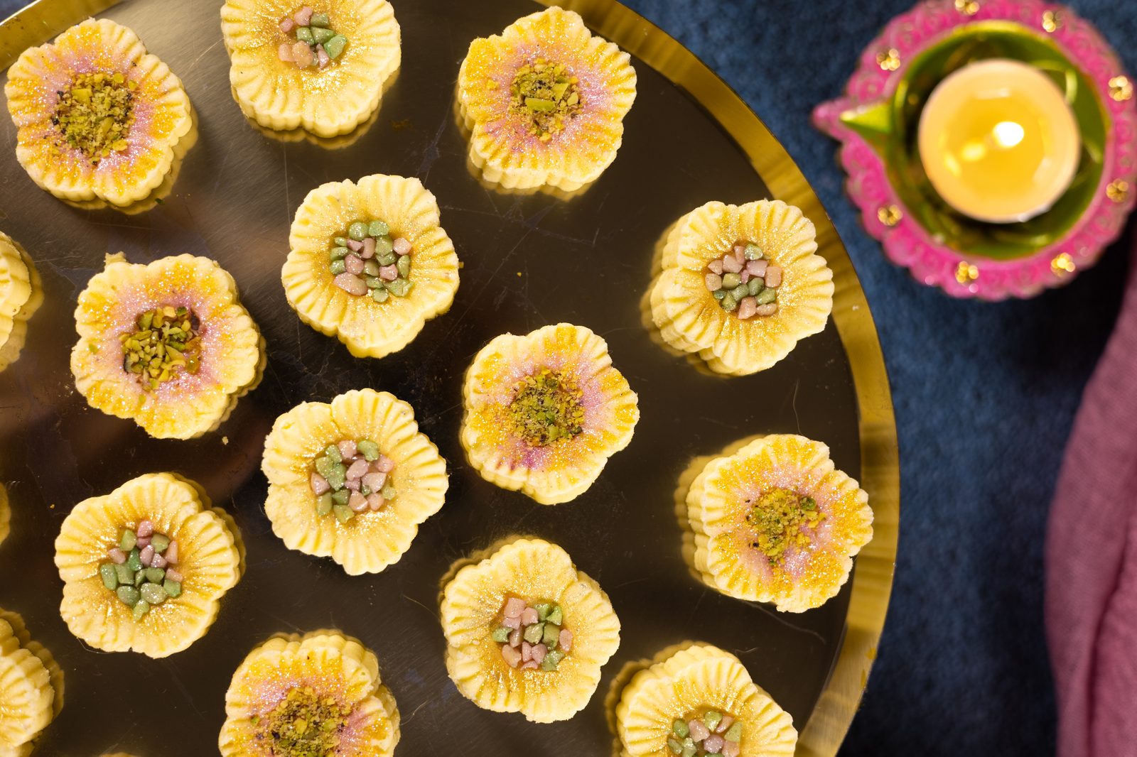 Simply wonderfuls on a gold plate beside a lit diya, from above