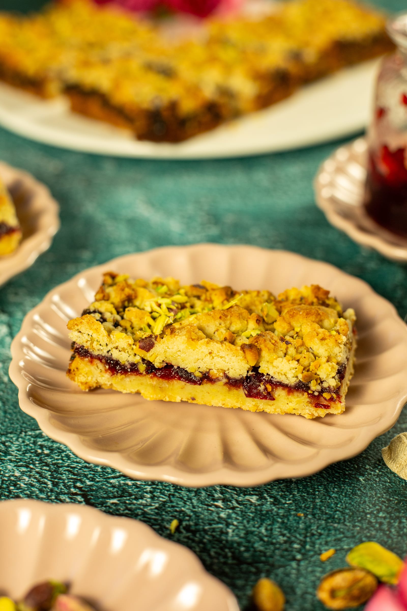A bar of plum and pistachio Hungarian tart on a pink plate