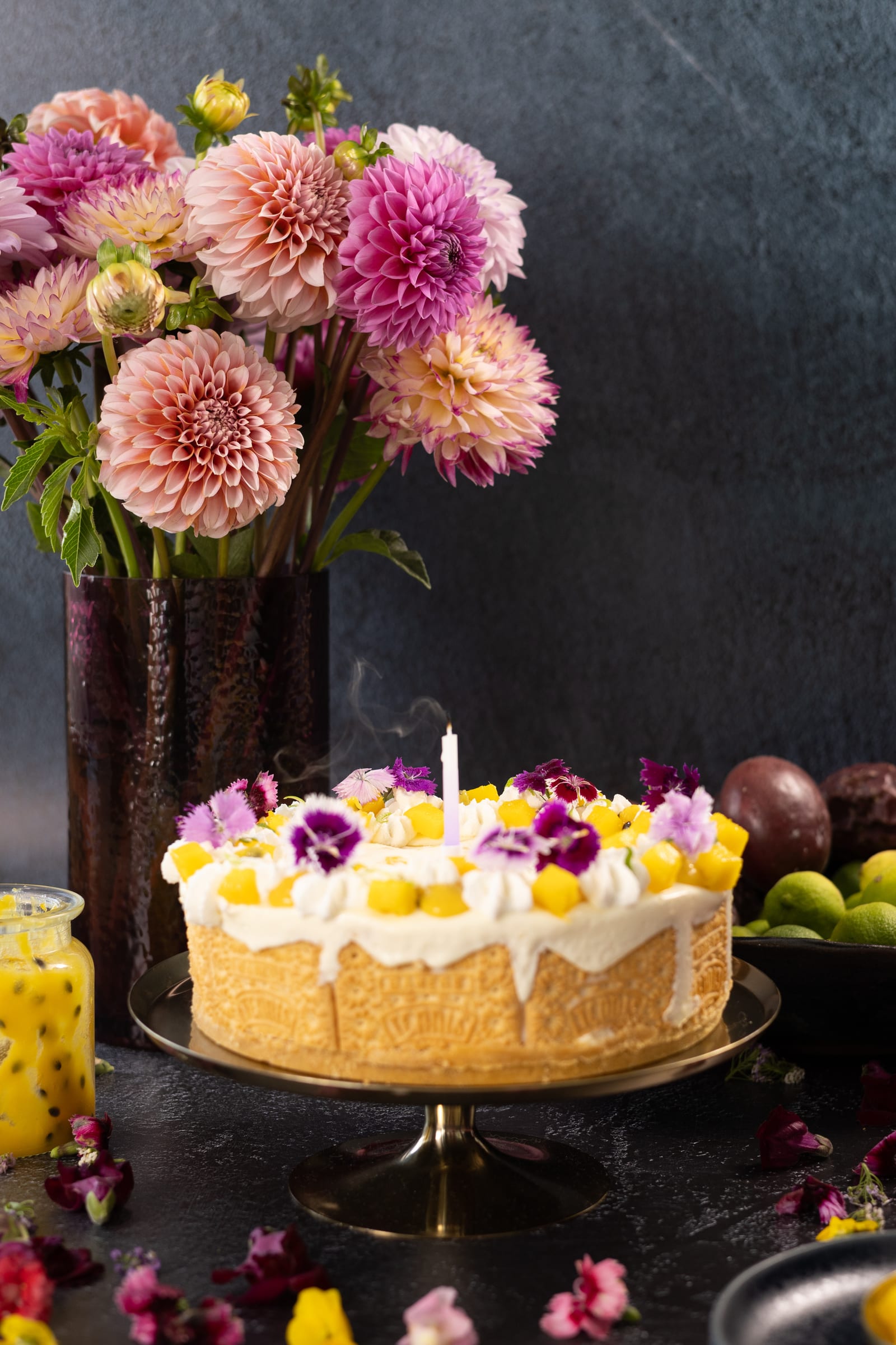 The ice cream cake on a stand beside a vase of dahlias