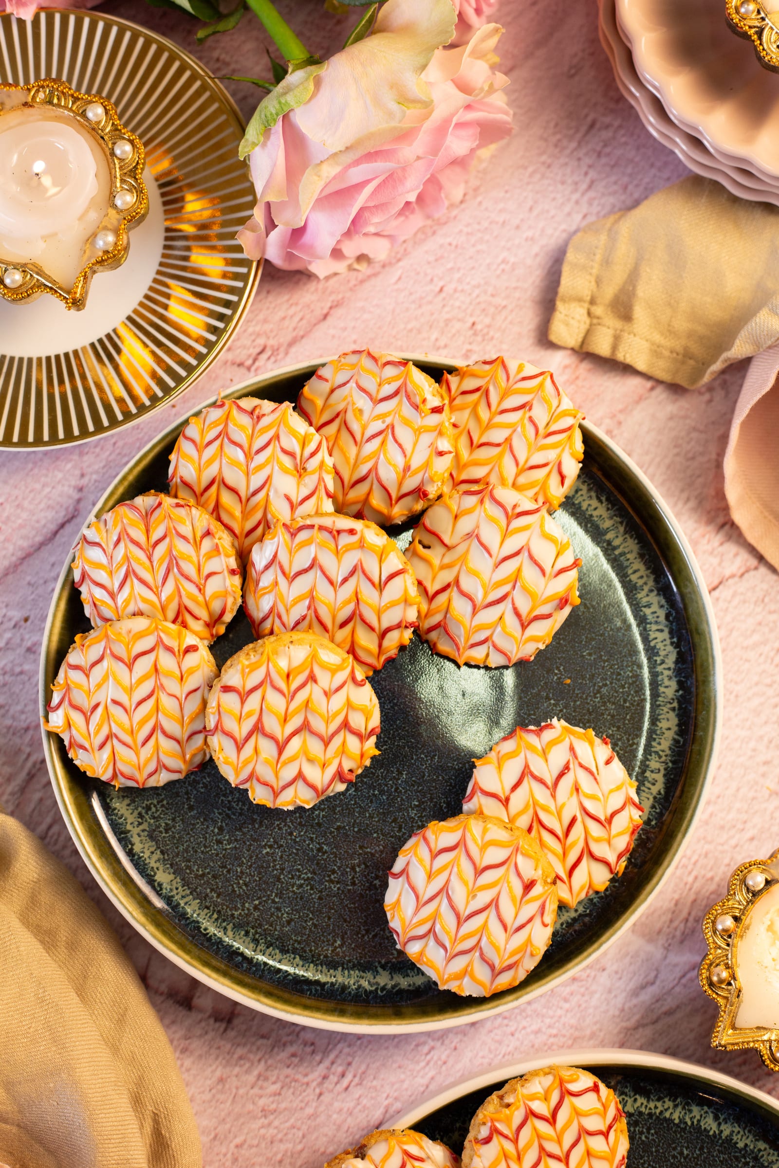 A plate of coconut and almond biscuits with pink and orange chevron icing, from above