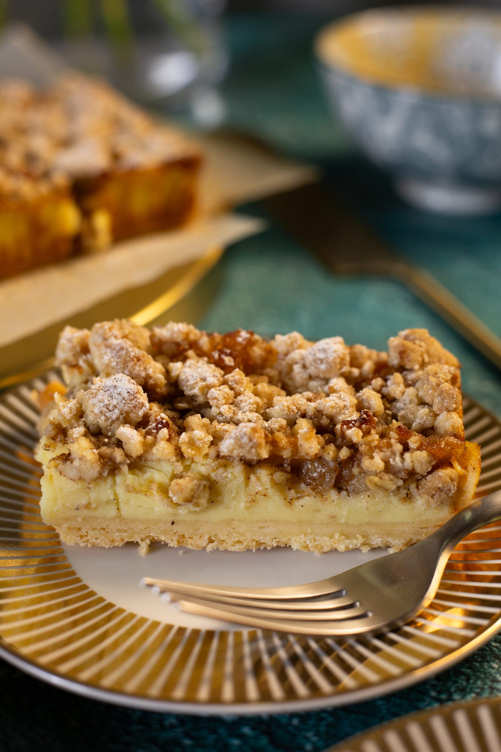 A slice of milk tart crumble bar on a gold plate with a fork