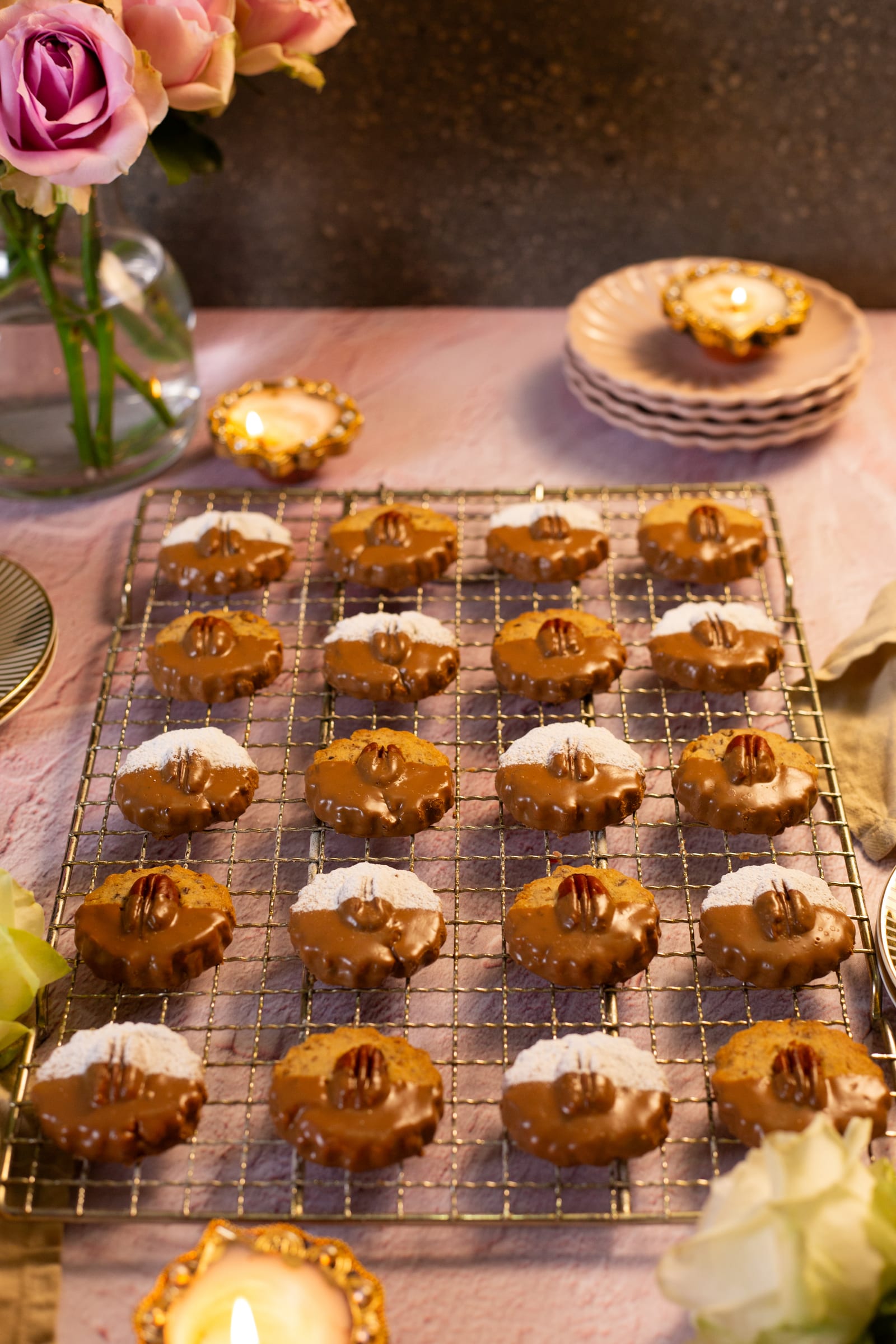 A wire rack of pecan nut biscuits with roses and a teacup behind