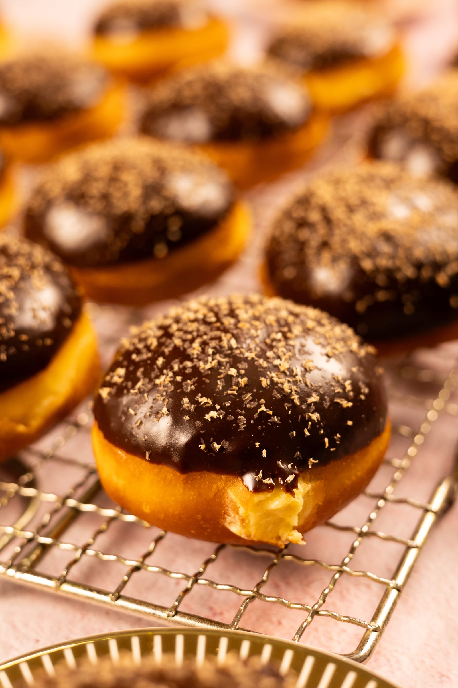 A chocolate-glazed brioche donut with milk tart filling on a wire rack