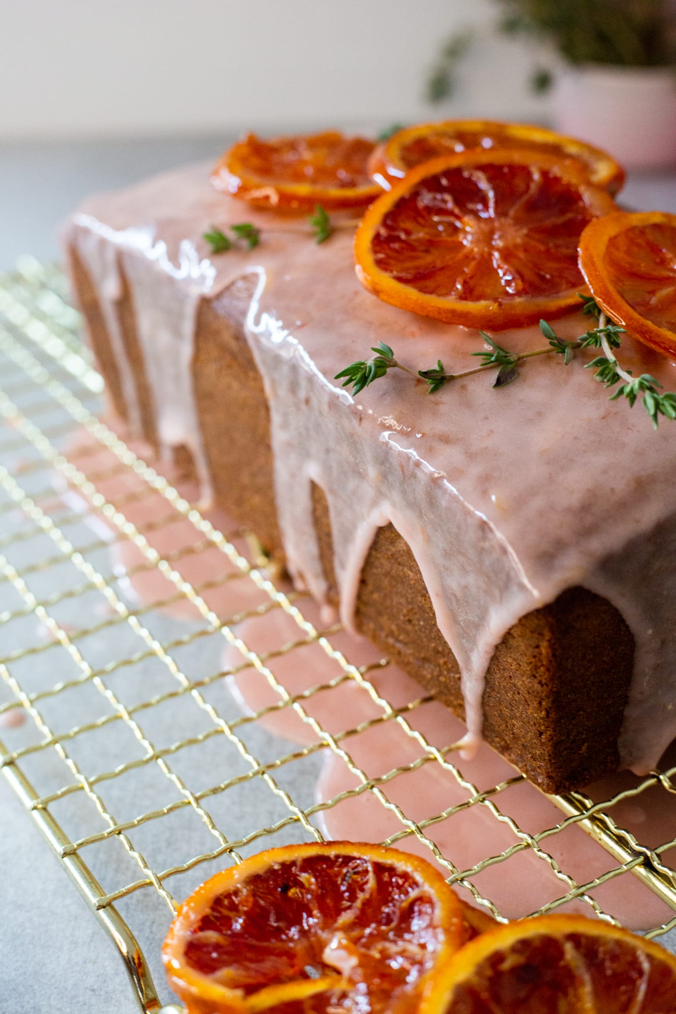 Close-up of the pink glaze drips and candied orange slices on a cream cheese pound cake