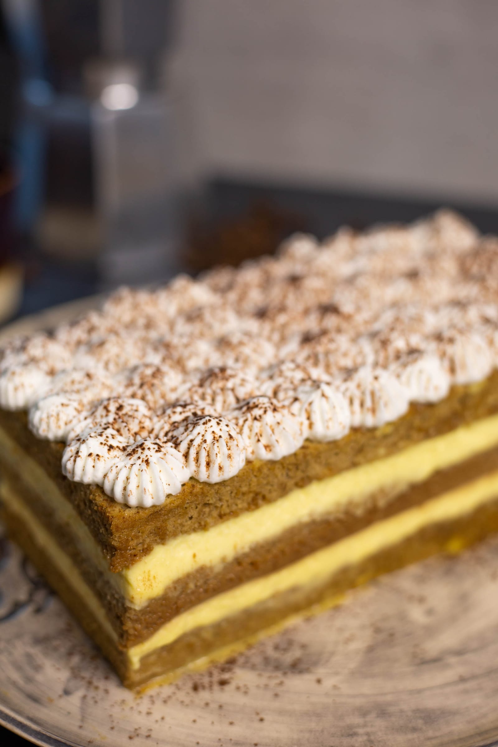 Close-up of the cake's coffee sponge and mascarpone layers under cocoa-dusted piping