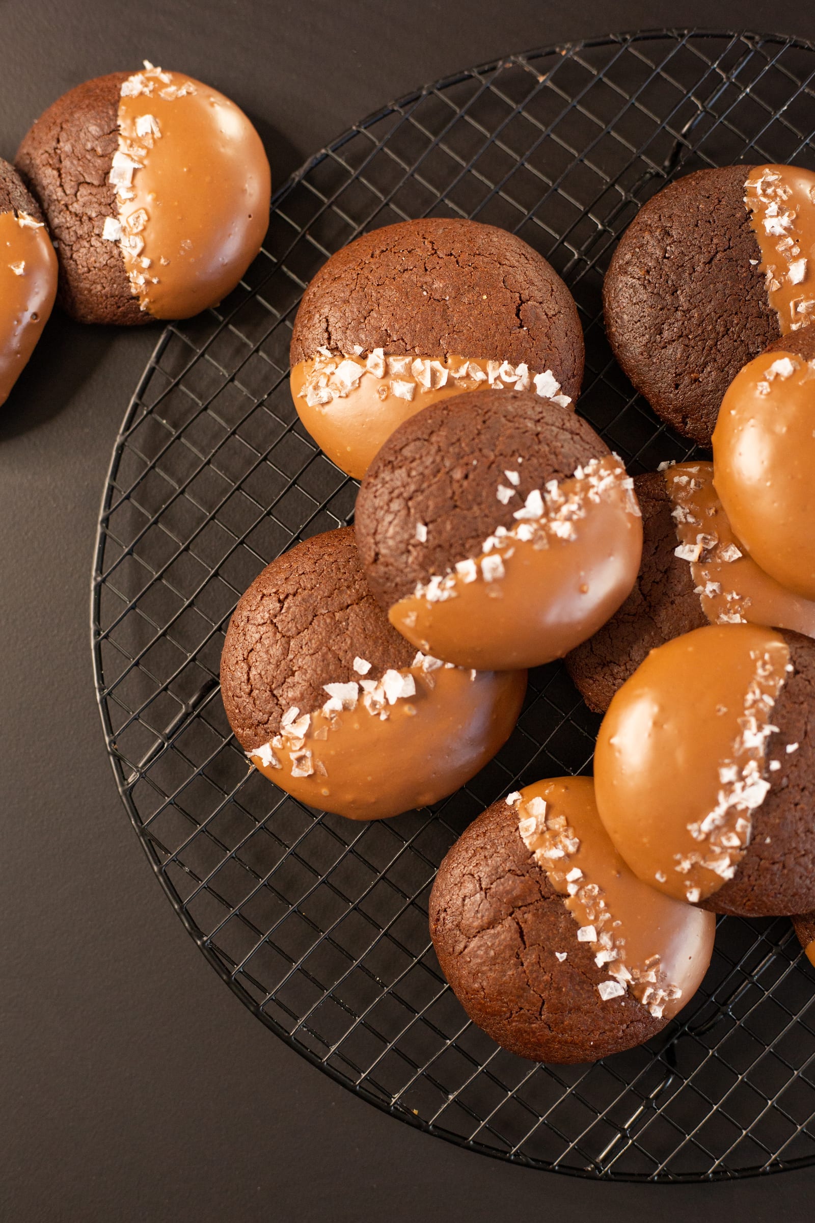 A pile of chocolate-dipped rye brownie cookies sprinkled with flaky salt