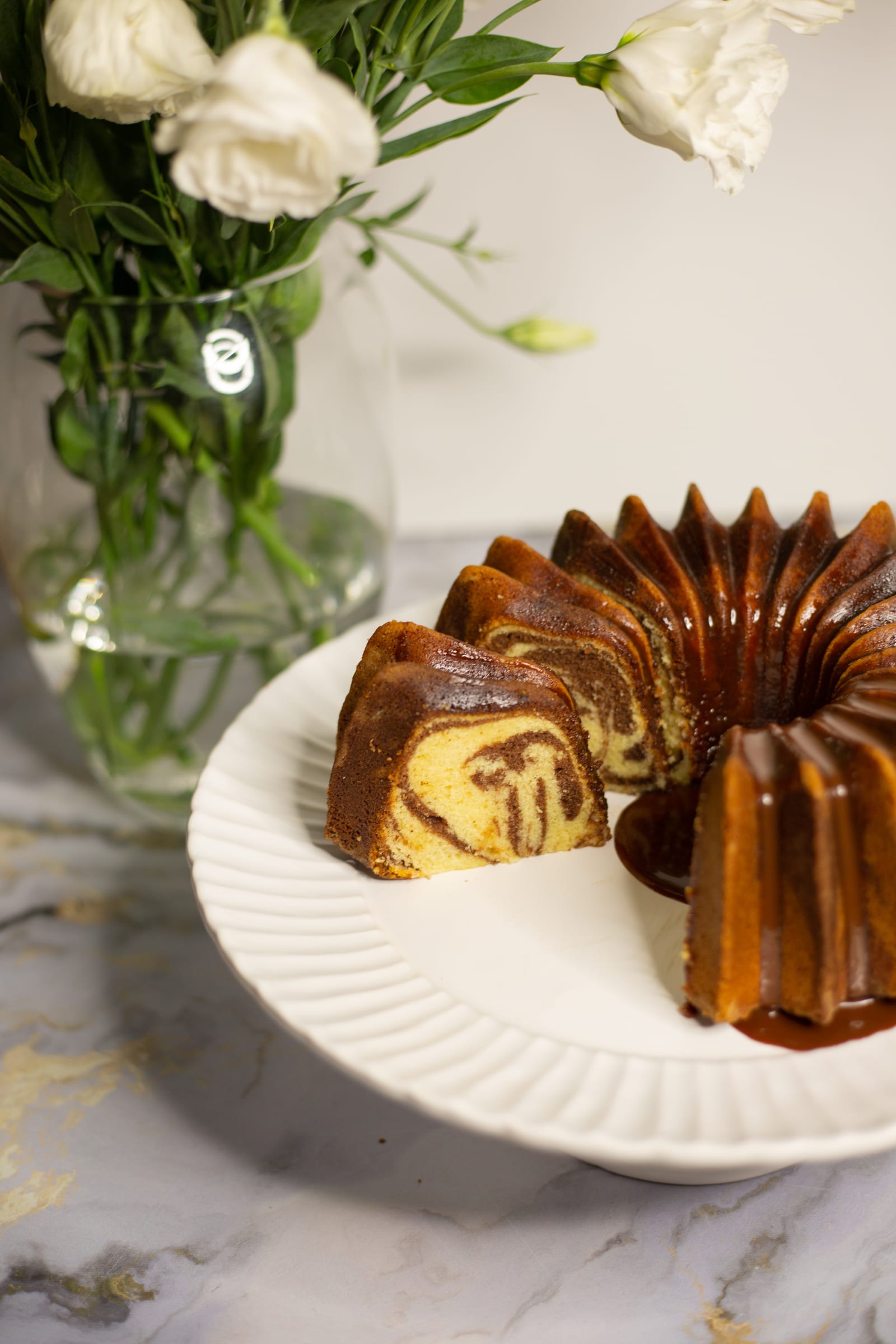 The cut marble pound cake on a fluted plate, its marbled inside showing
