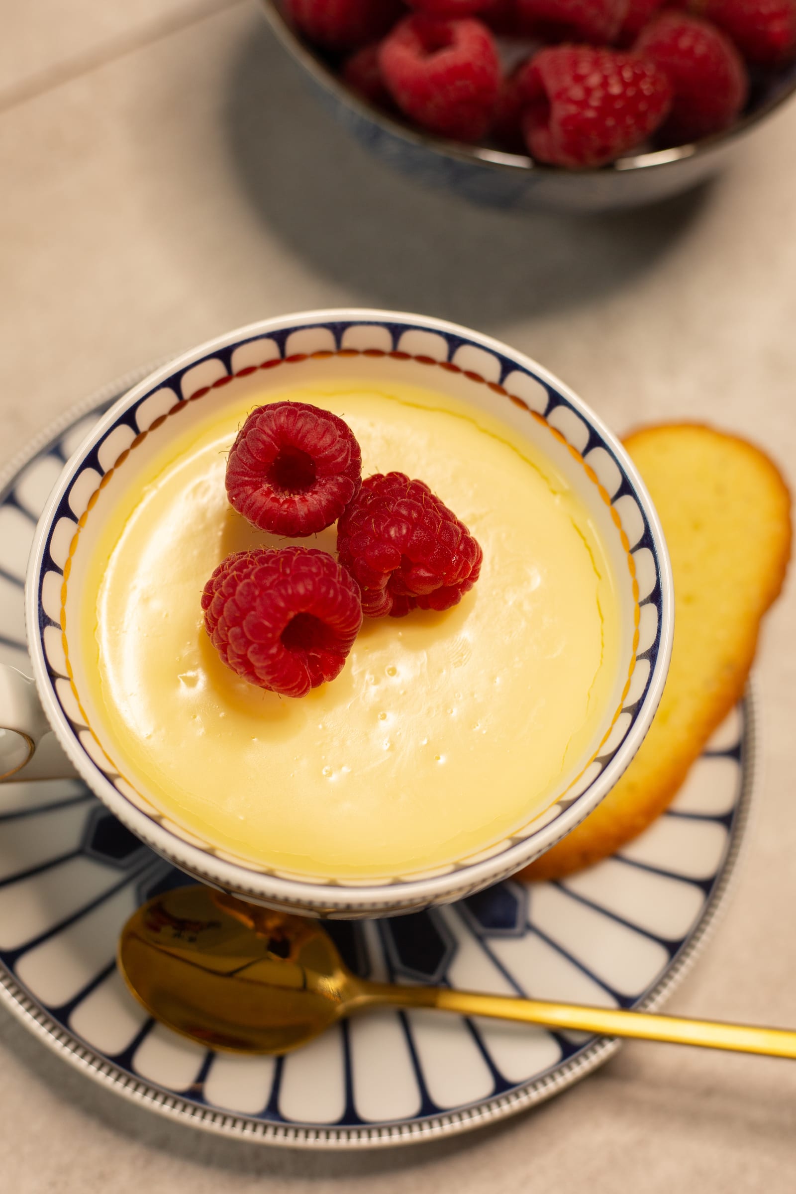 Looking down into a lemon posset at its smooth surface and raspberries