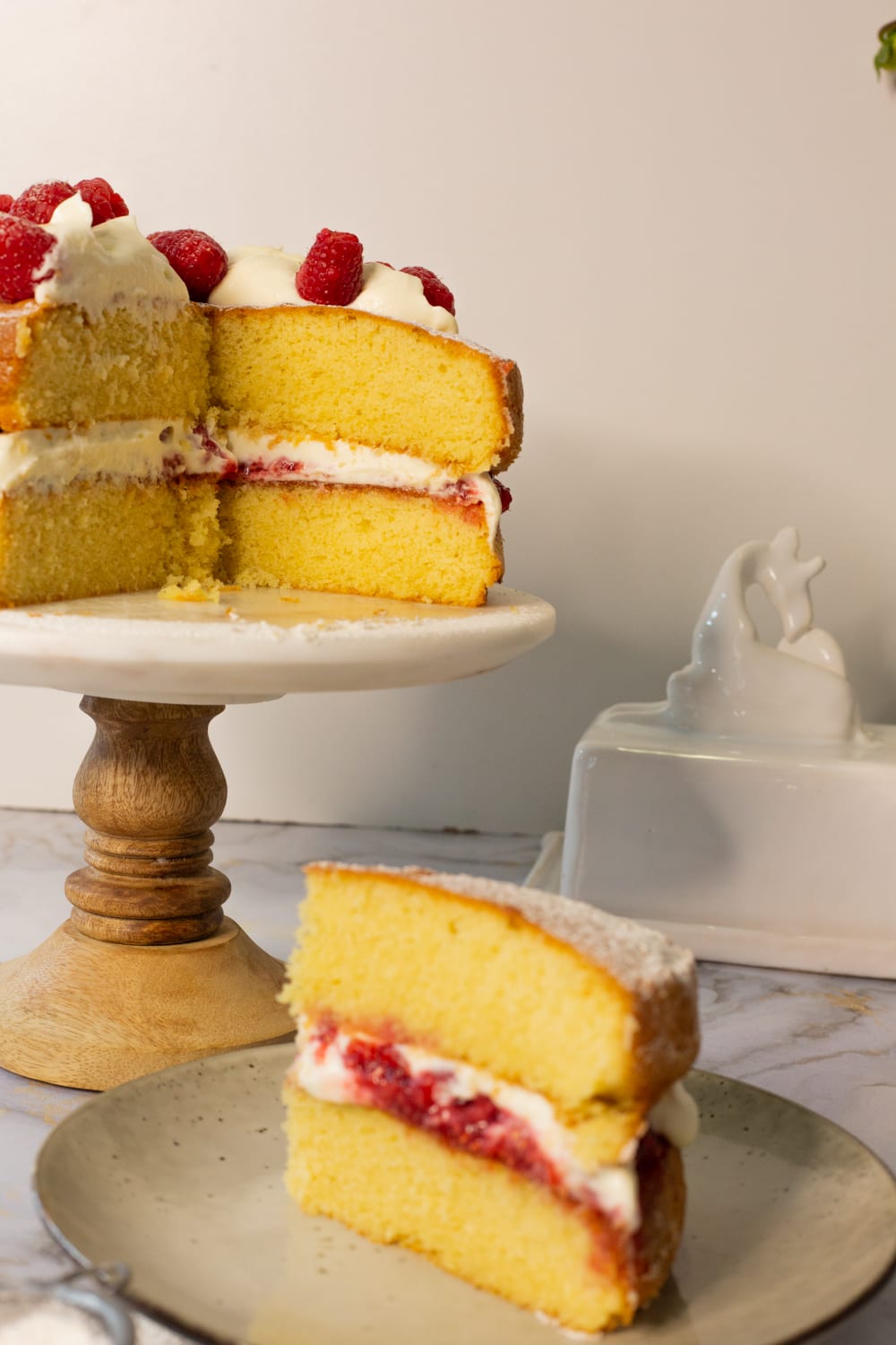 A slice of Victoria sandwich on a grey plate, its layers of sponge, compote and cream facing out