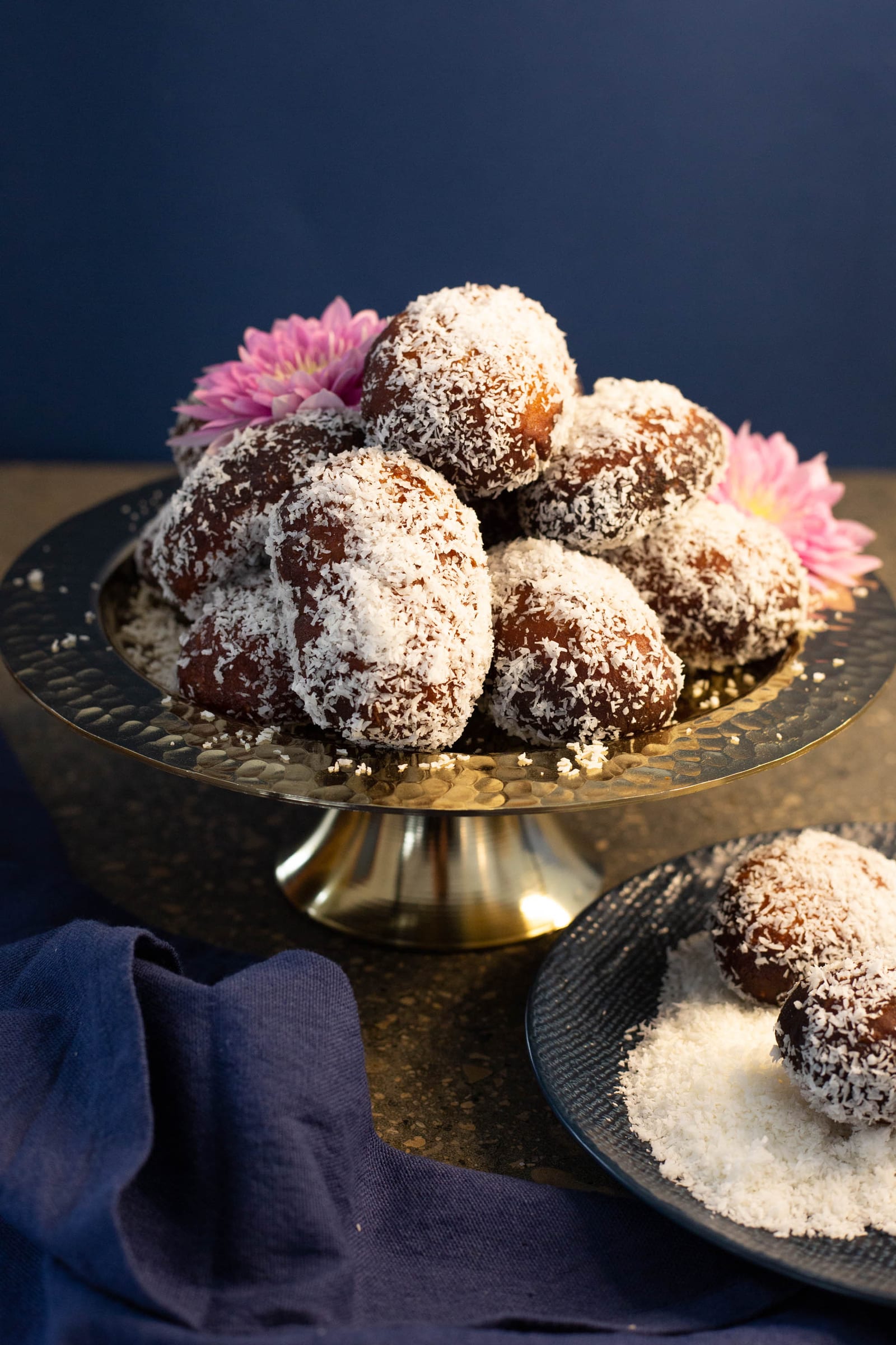 A pile of Cape Malay koesisters on a footed brass bowl, with a side plate of coconut