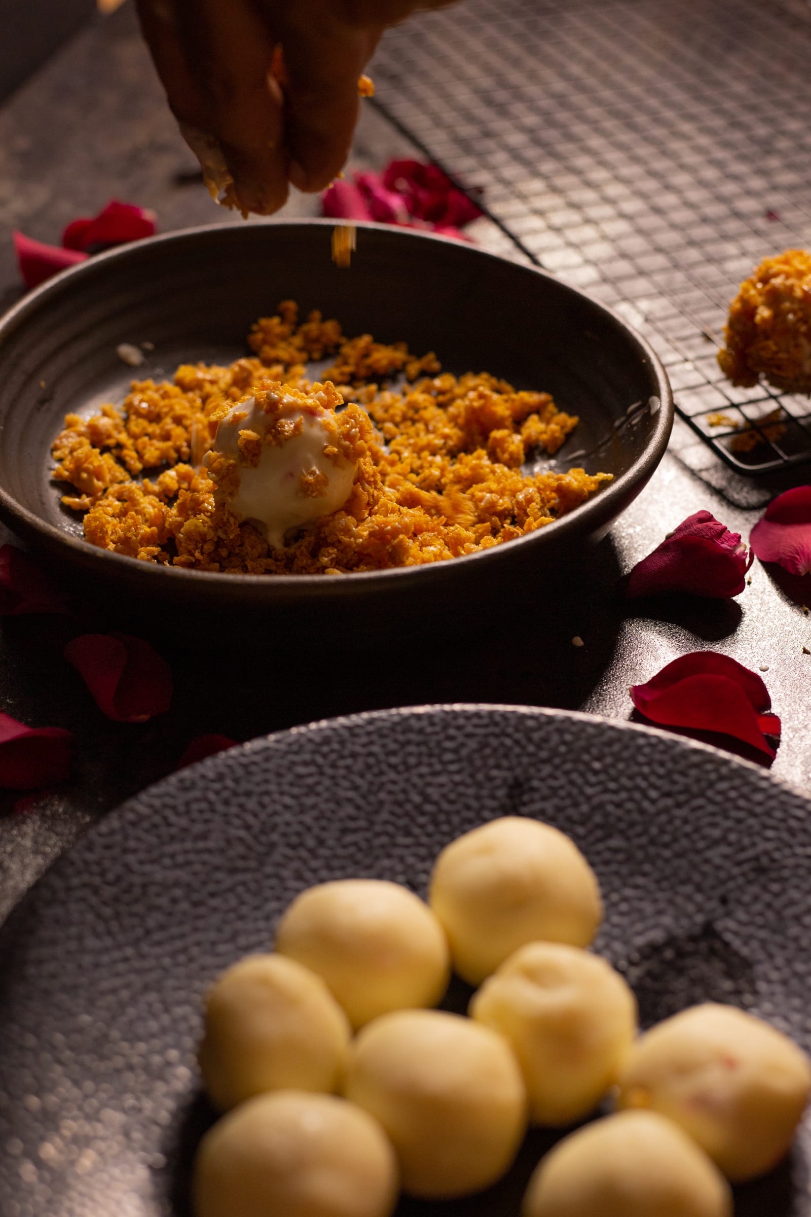 Plain white chocolate truffle centres beside a bowl of cornflake crunch, from above
