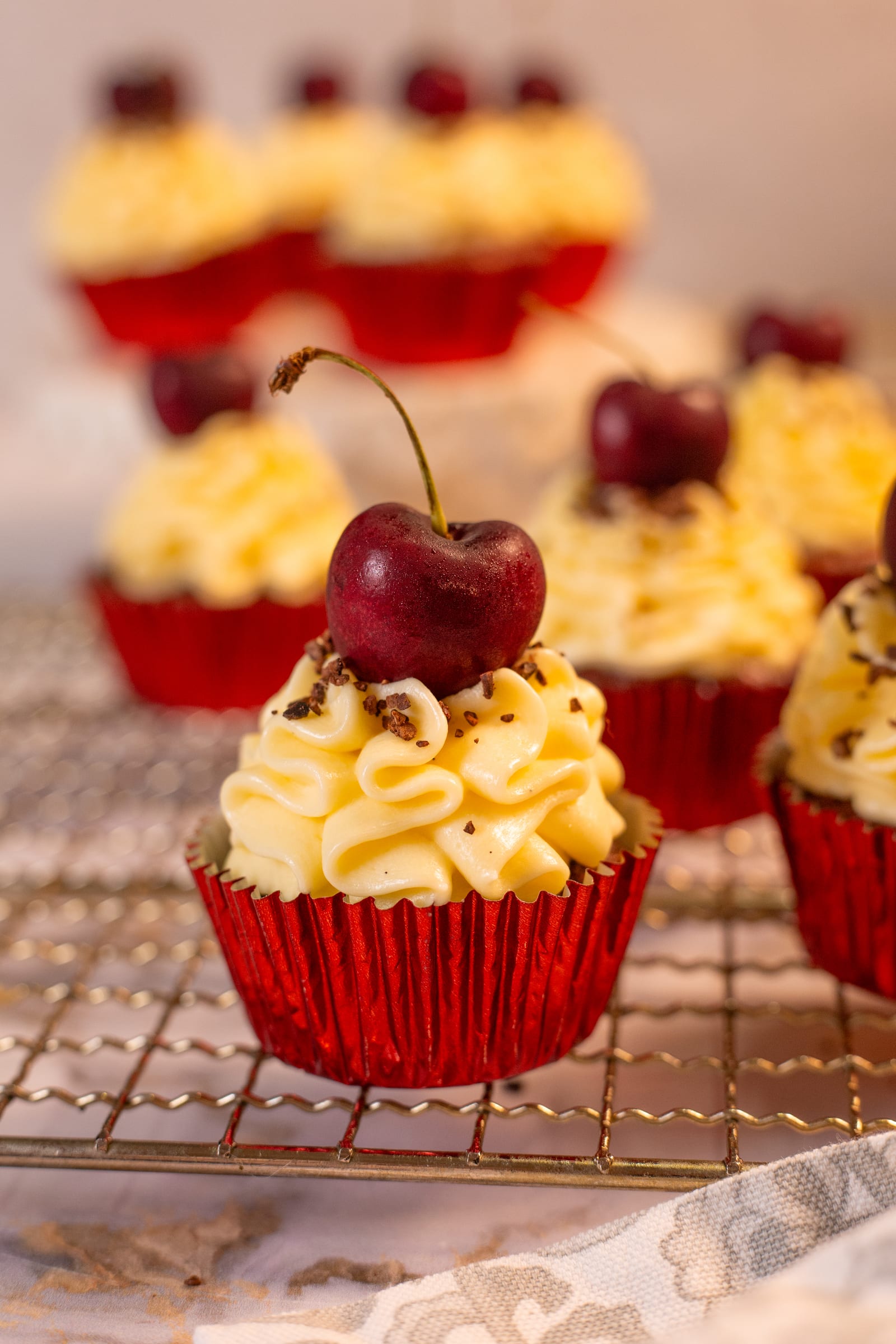 A red velvet cupcake topped with cream cheese frosting and a cherry