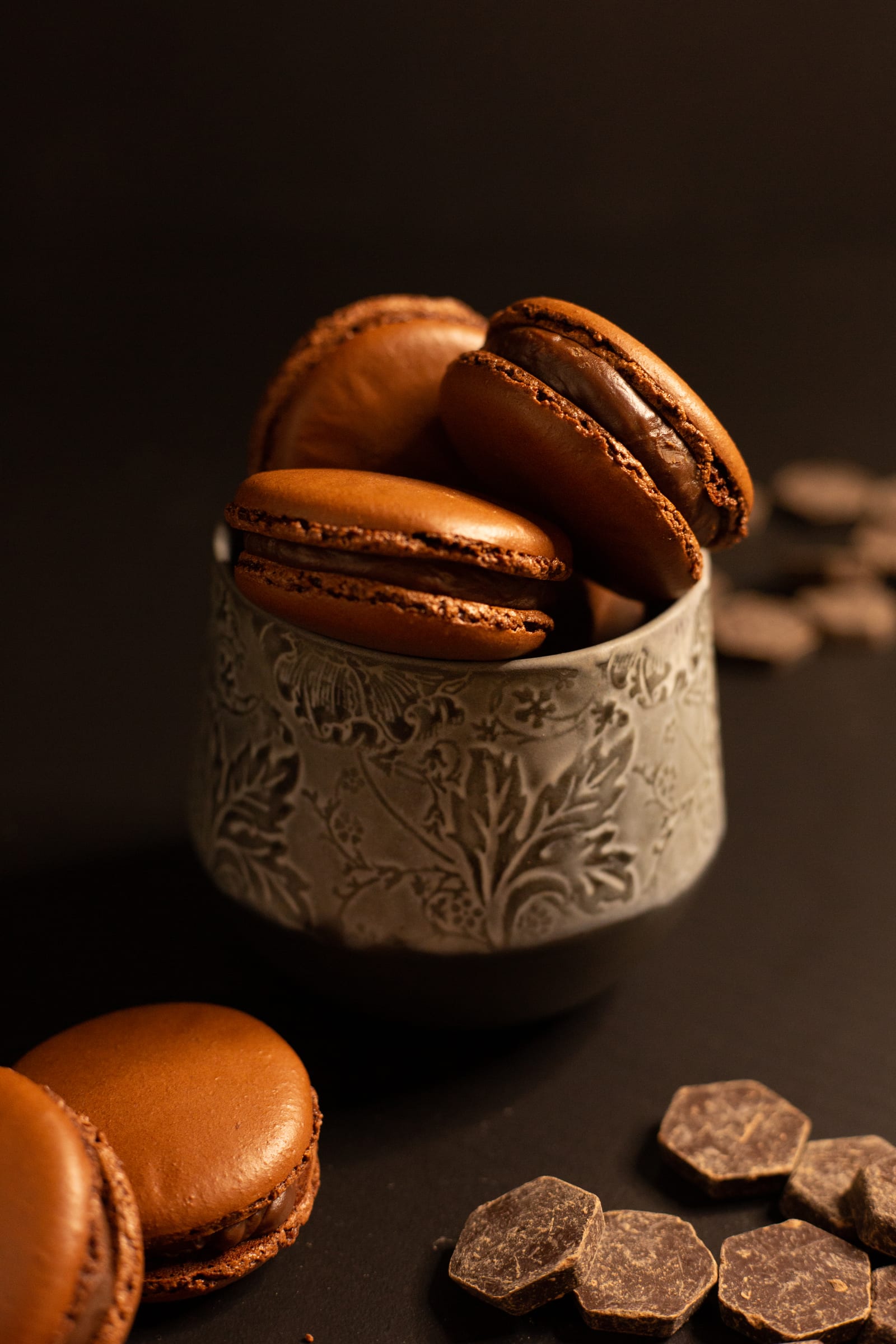 Chocolate macarons sandwiched with chocolate ganache, piled in a ceramic cup