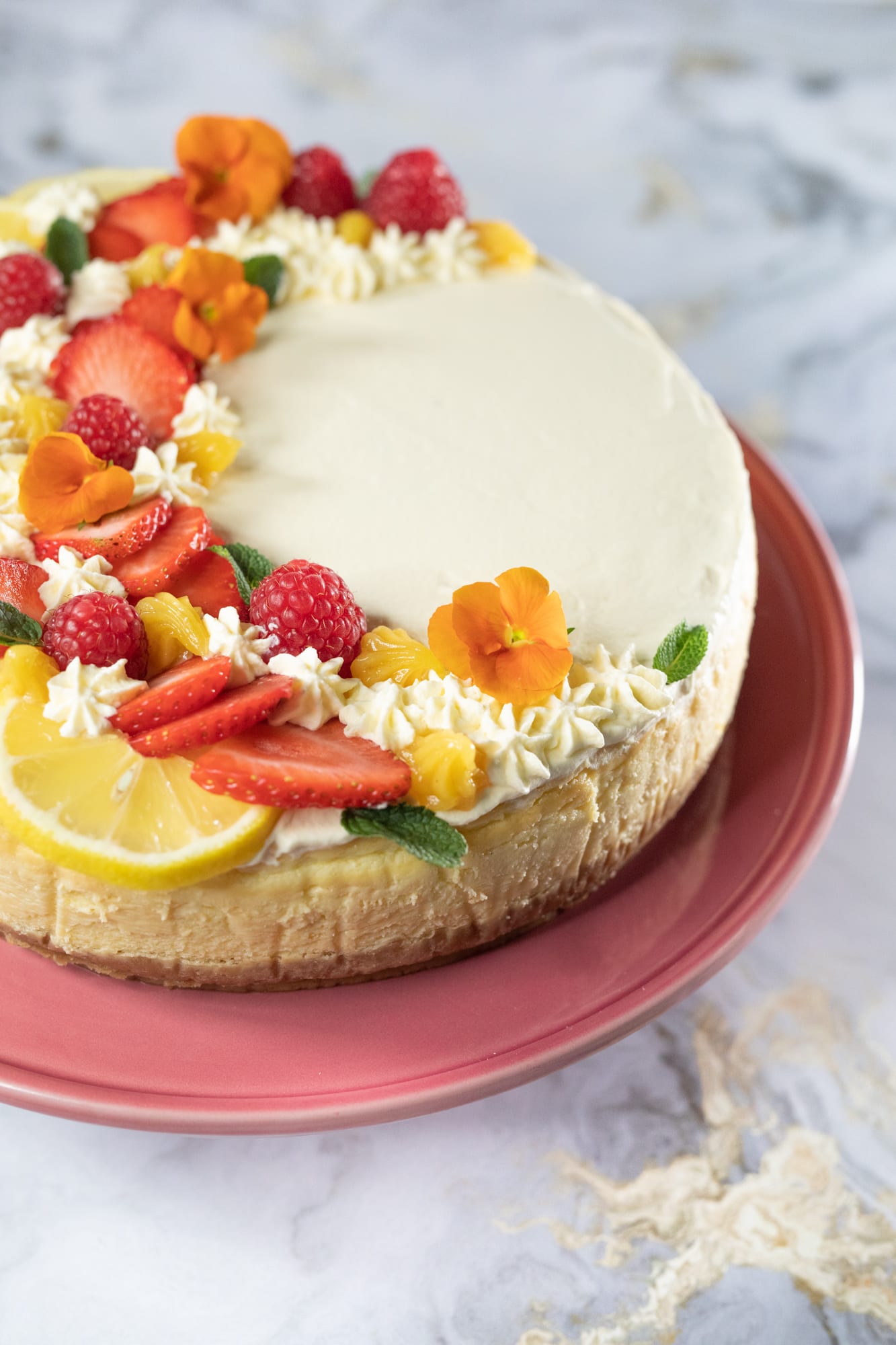 The lemon slices, berries and cream on a creamy lemon cheesecake, from the side