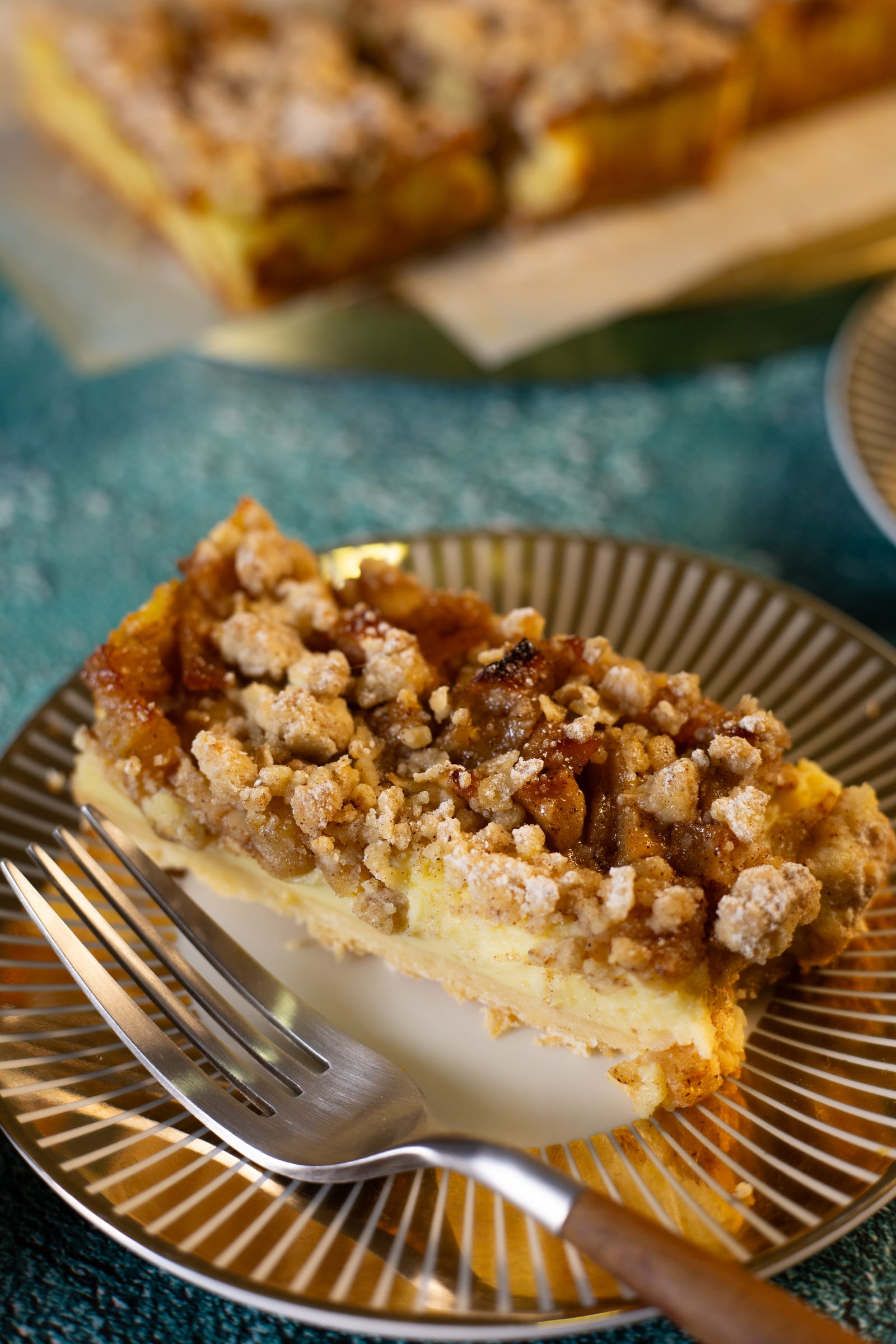 Close-up of a slice showing the shortbread base, milk tart filling and crumble
