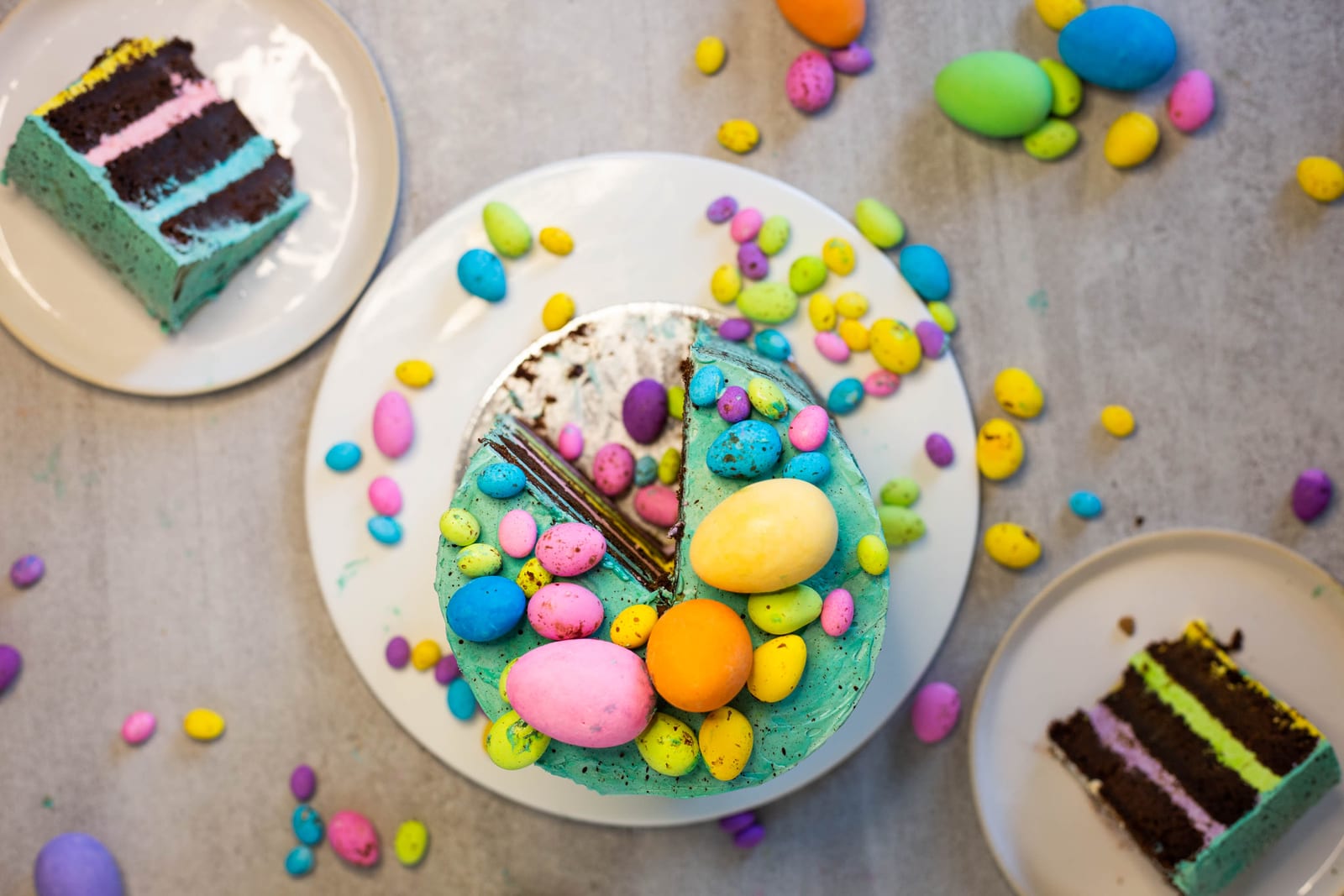 A cut speckled egg cake with a wedge missing and slices on plates around it, from above