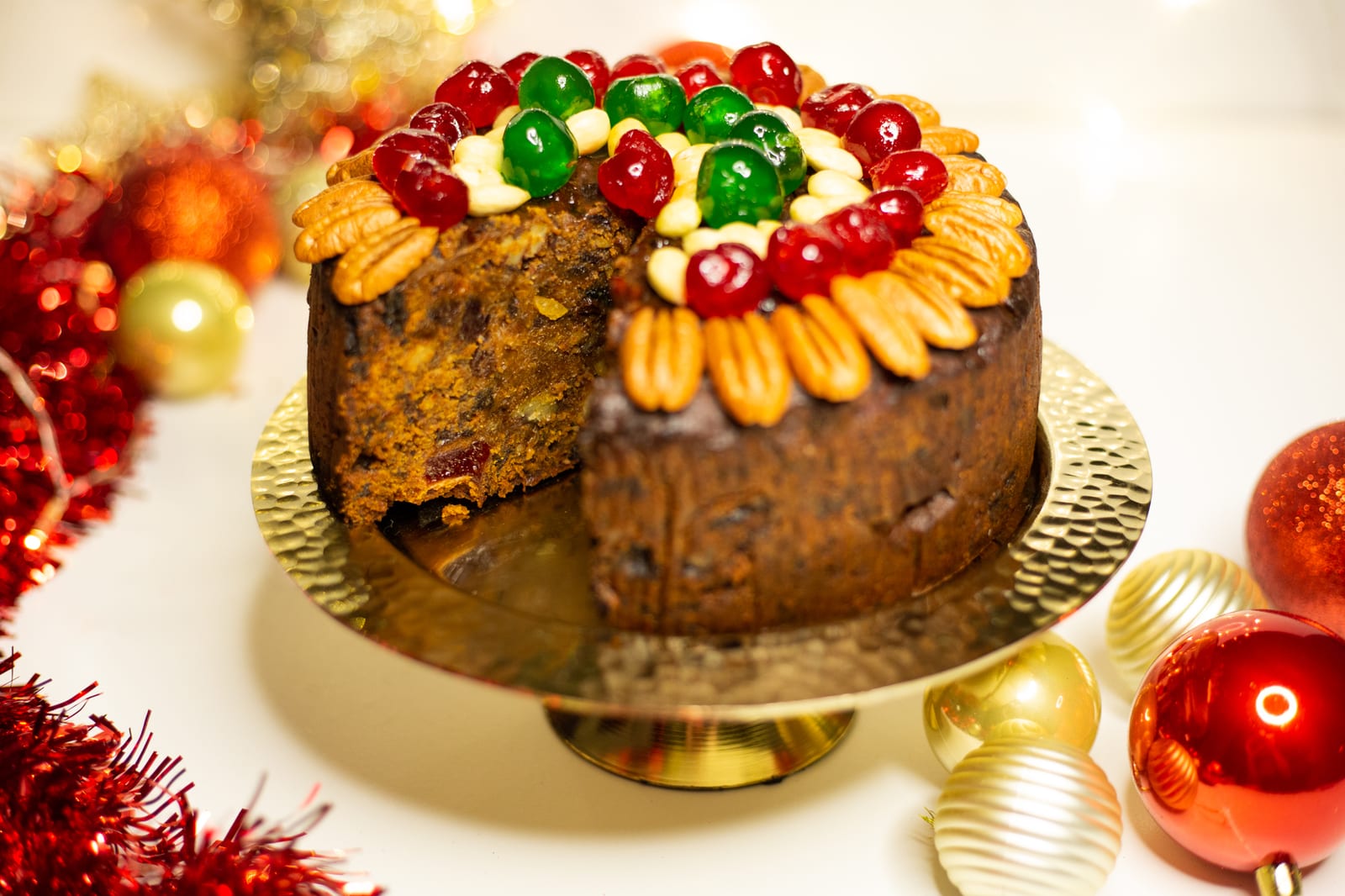 A boozy fruit cake with a wedge cut out, showing the dark fruit inside