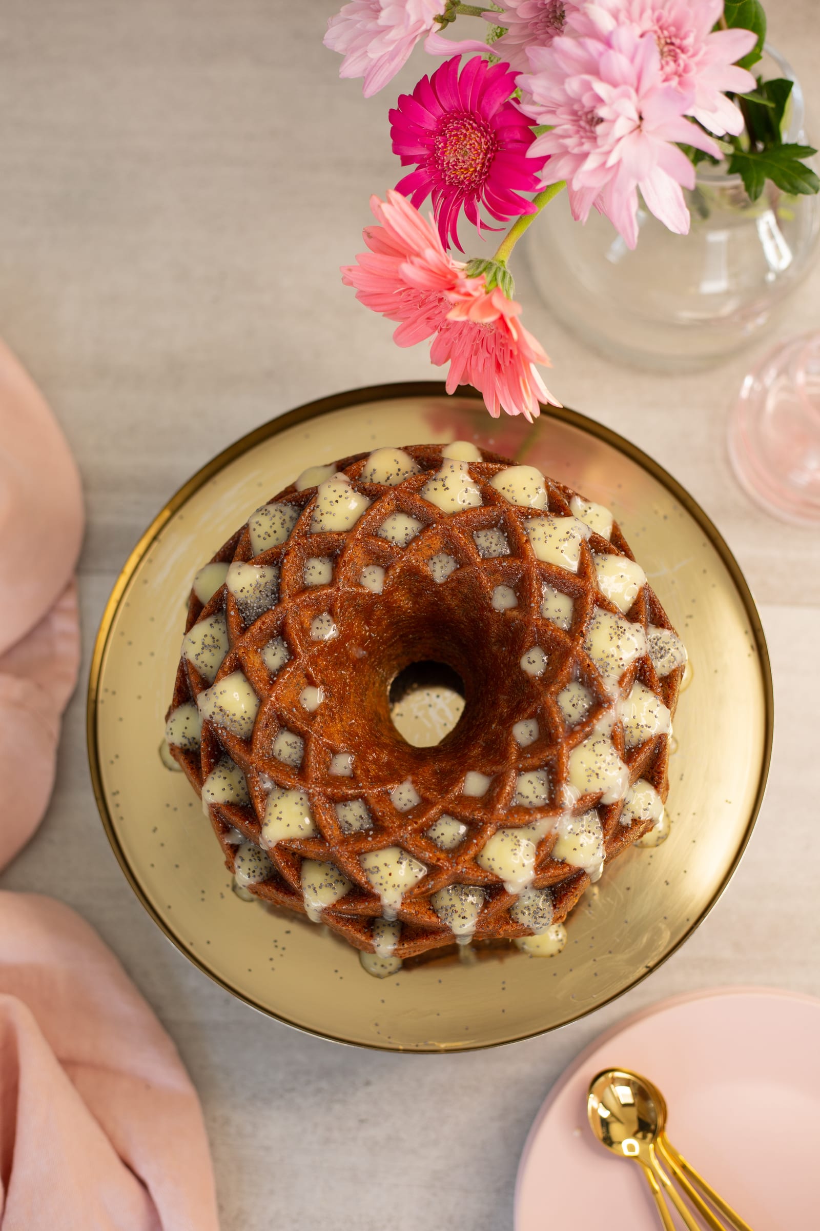 A glazed lemon, poppyseed and olive oil bundt on a gold platter, from above