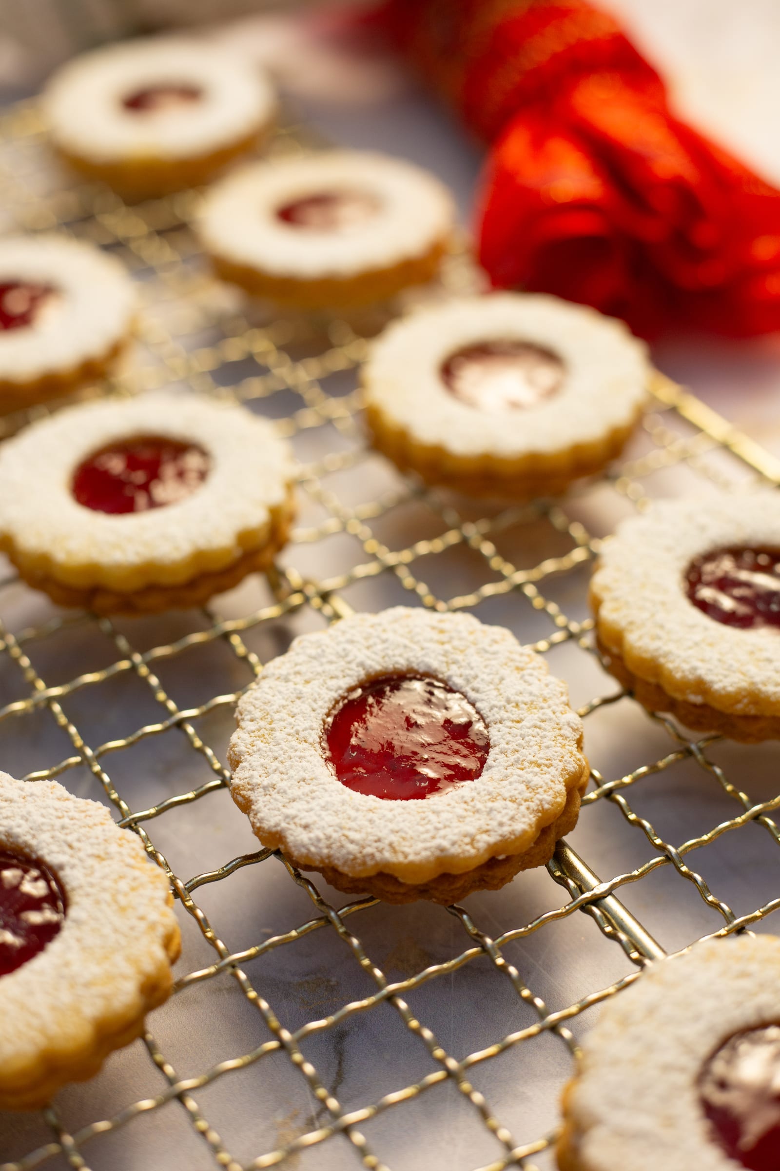 Close-up of round lemon and raspberry Linzer cookies on a wire rack, the jam showing through the windows
