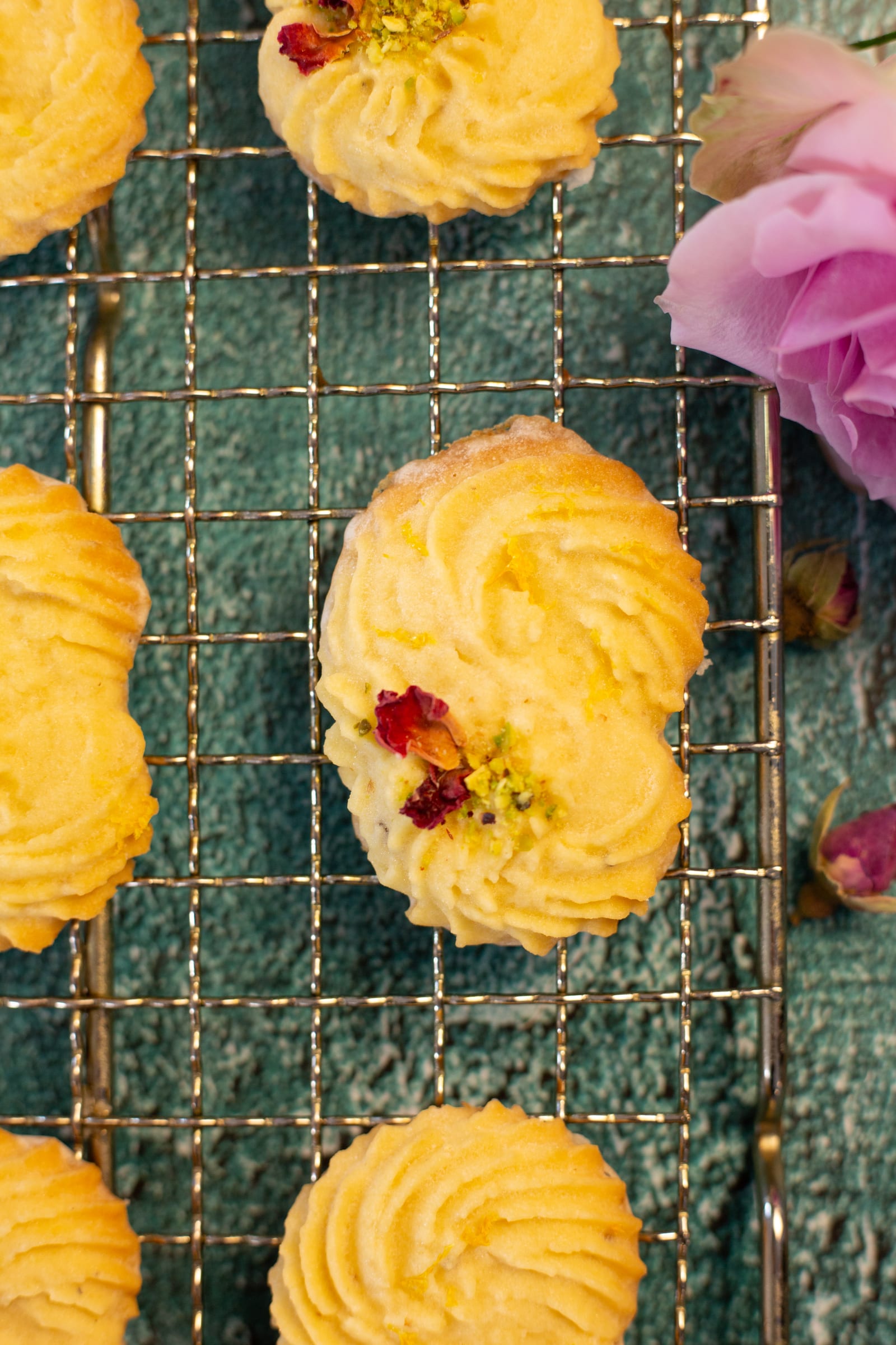 Close-up of a piped biscuit topped with rose petals and pistachio