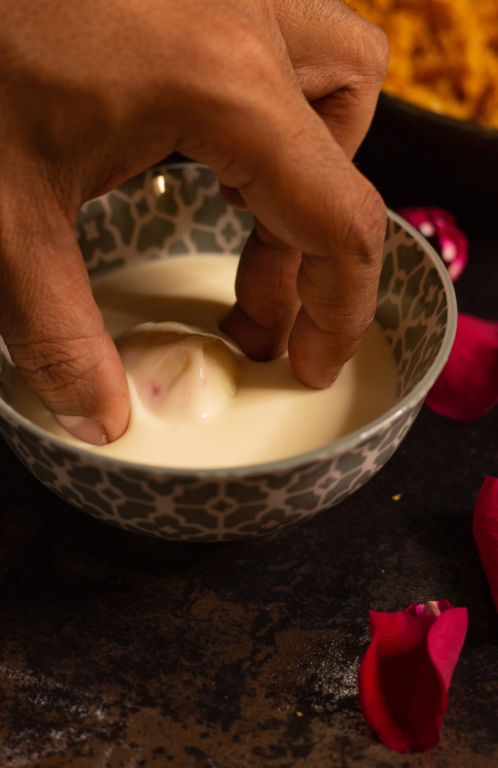 A truffle centre being dipped into melted white chocolate