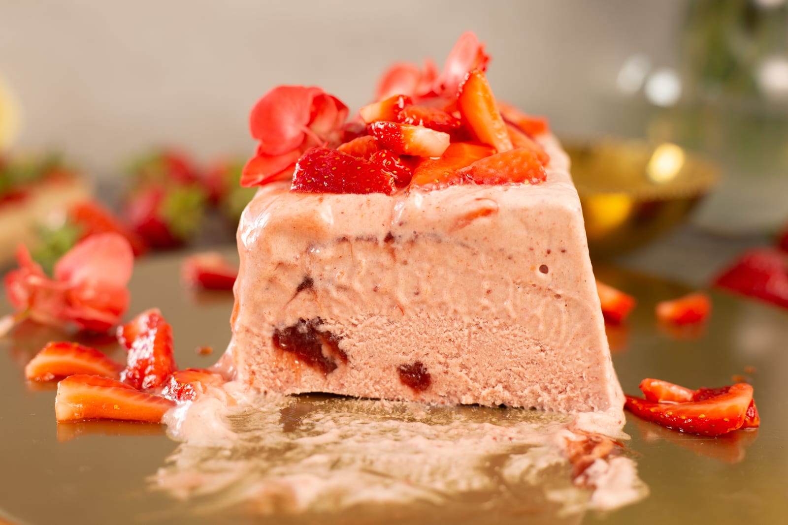 The cut end of a roasted strawberry and rosemary semifreddo, showing the pink interior with jam swirls under roasted strawberries
