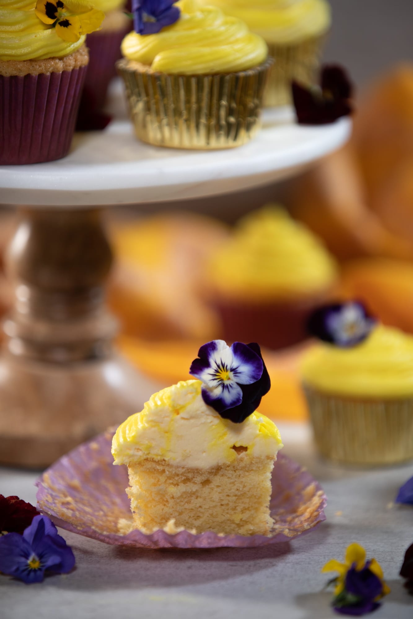 A vanilla cupcake cut open in front of a cake stand