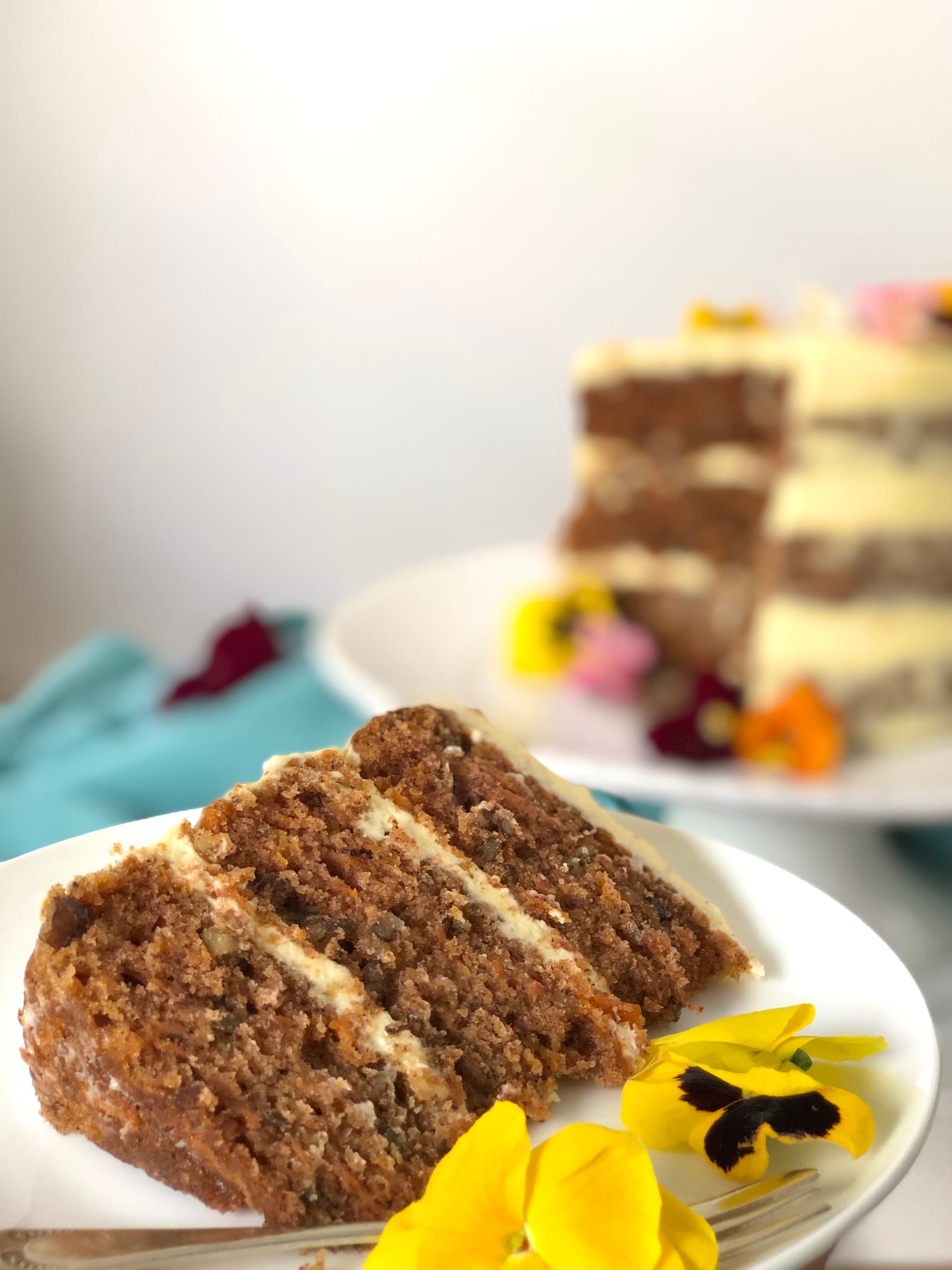 Close-up of a slice of carrot cake showing its crumb and layers of icing