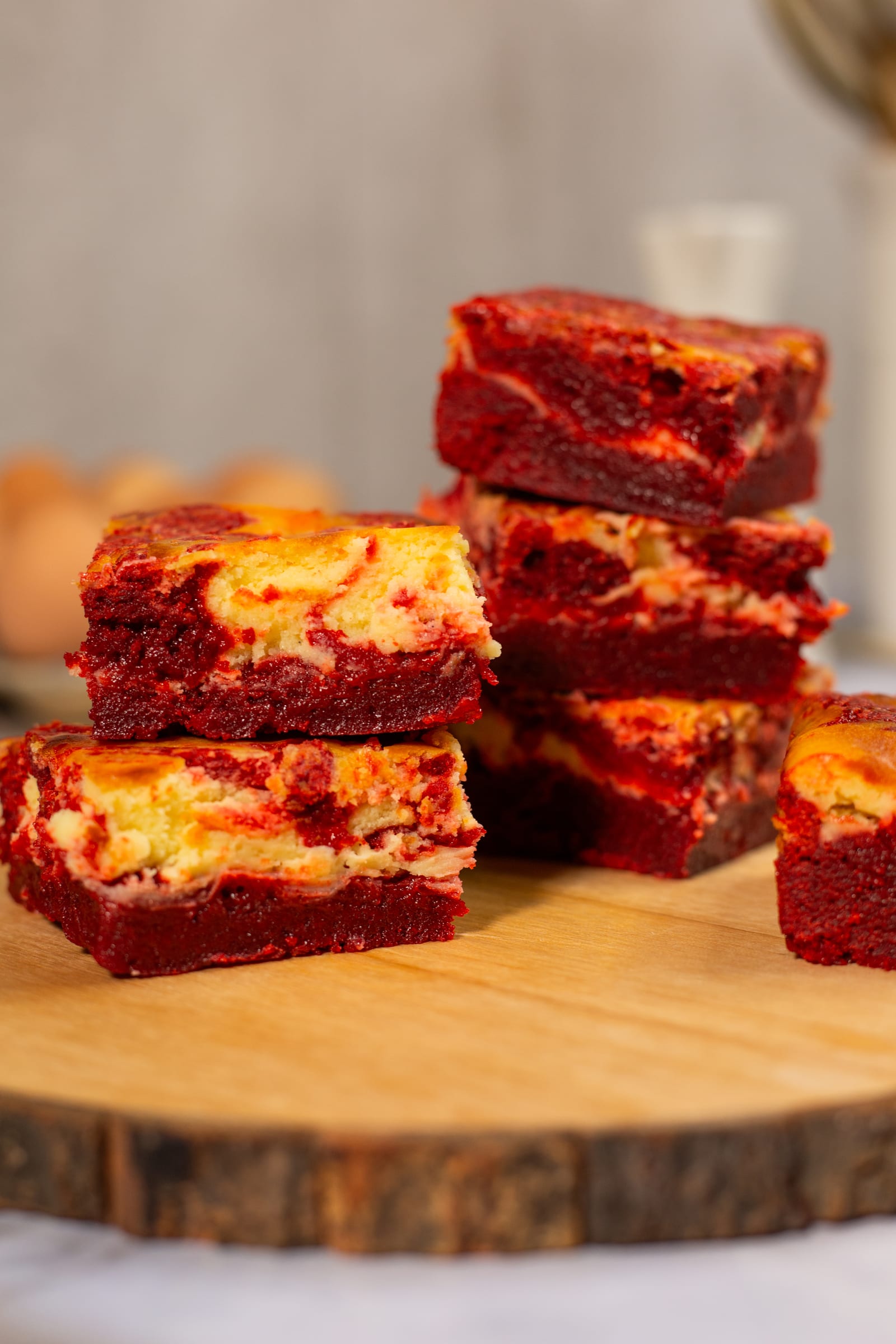 Stacks of red velvet cheesecake blondies on a wooden board, close up