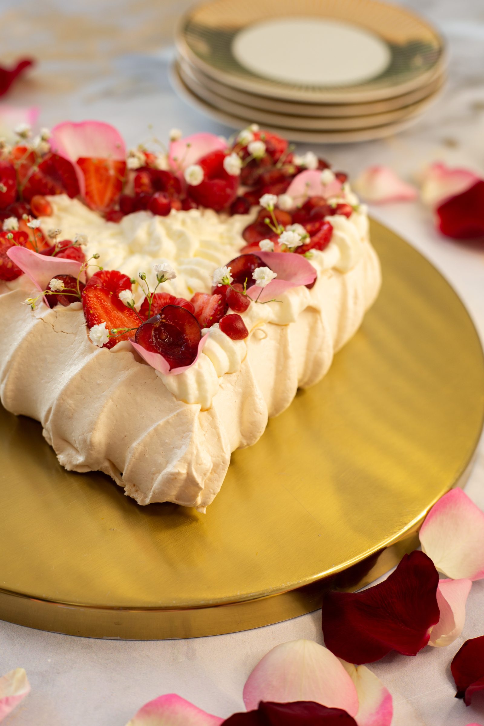 A berry pavlova heart showing its tall ridged meringue sides, from a low side angle