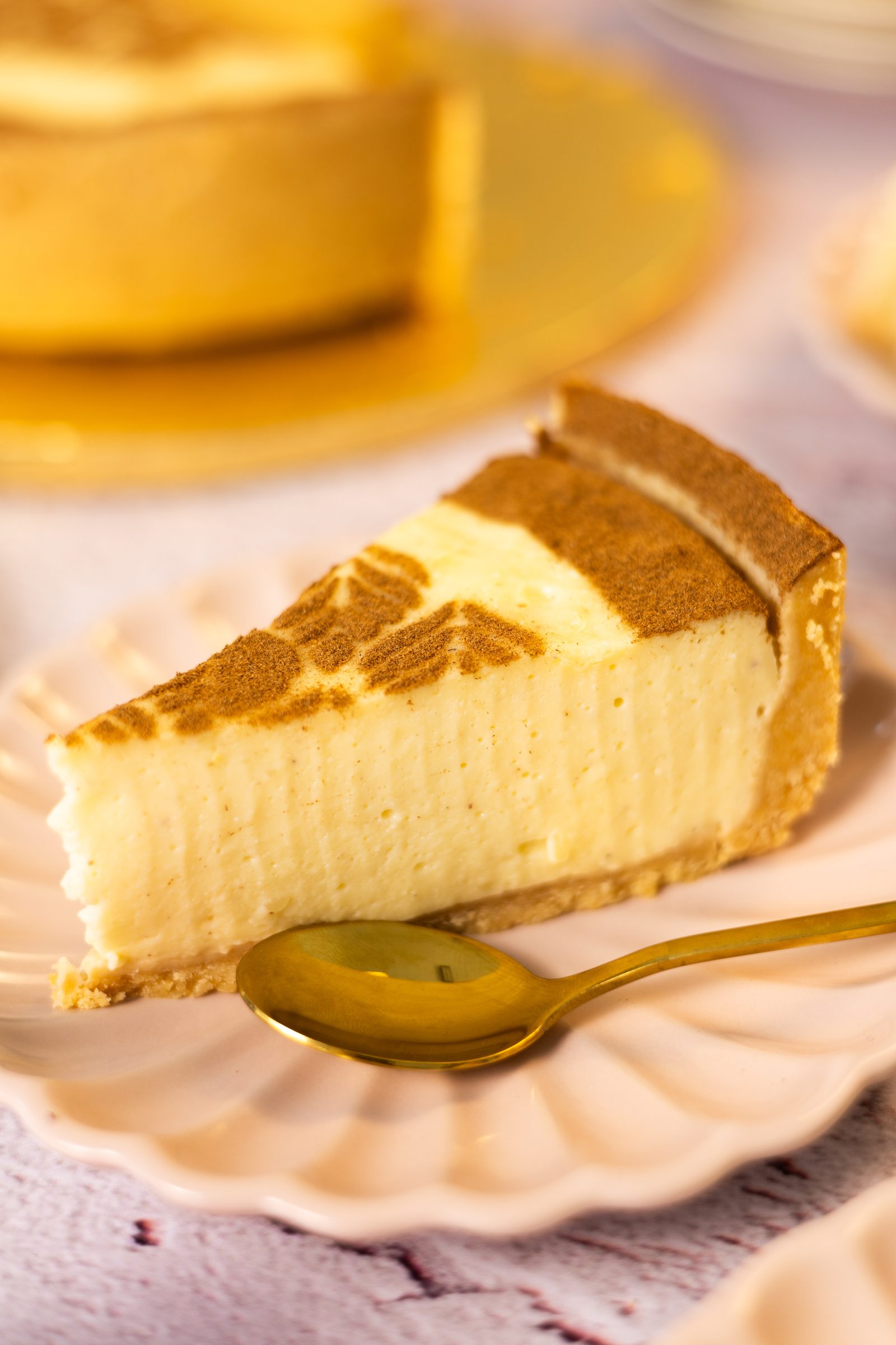 A close-up of a slice of no bake milk tart showing the smooth set filling and the crumb base, with a gold spoon