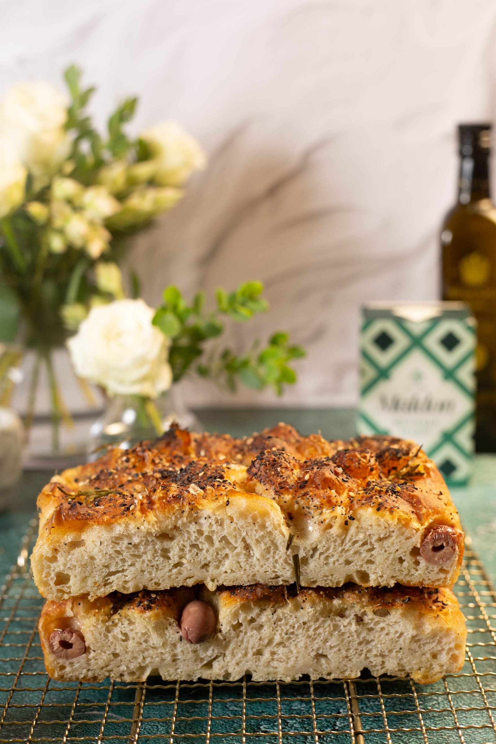 Two pieces of focaccia stacked, with flowers and olive oil