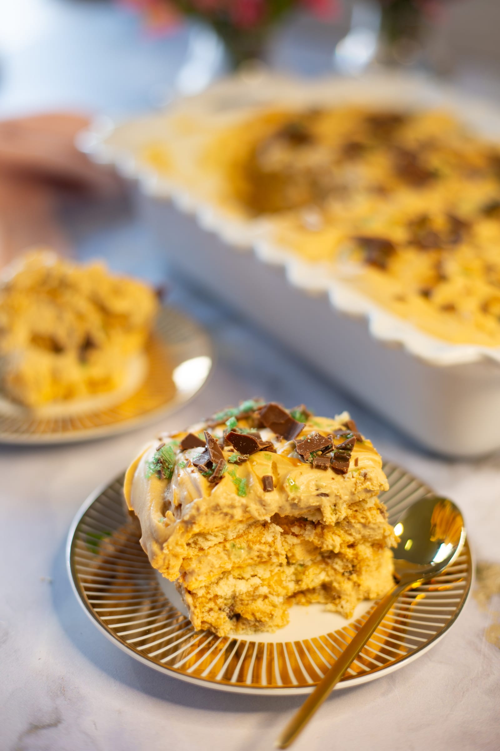 A serving of Peppermint Crisp tart on a gold-rimmed plate in front of the dish
