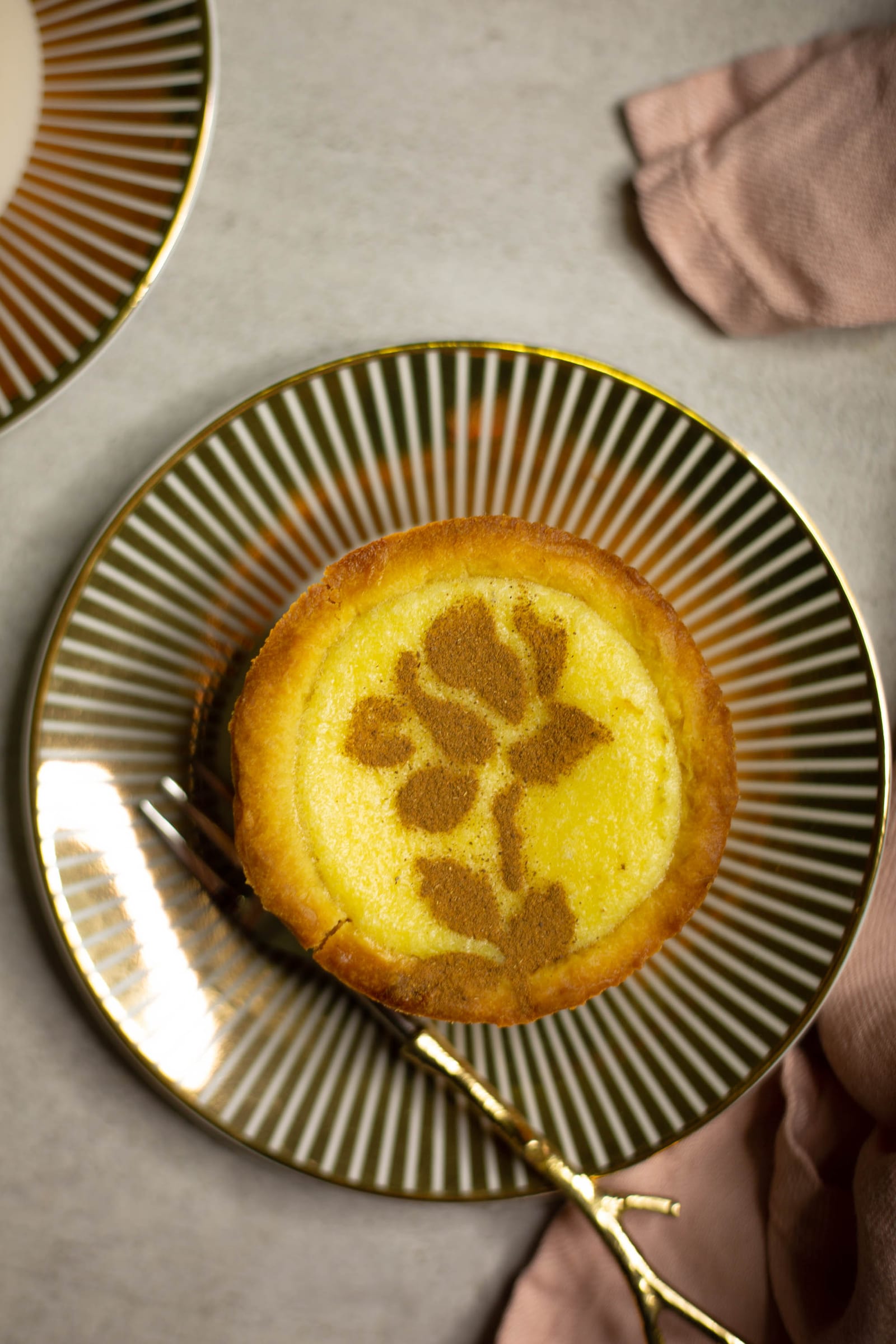 A mini milktart on a striped gold-rimmed plate, from above