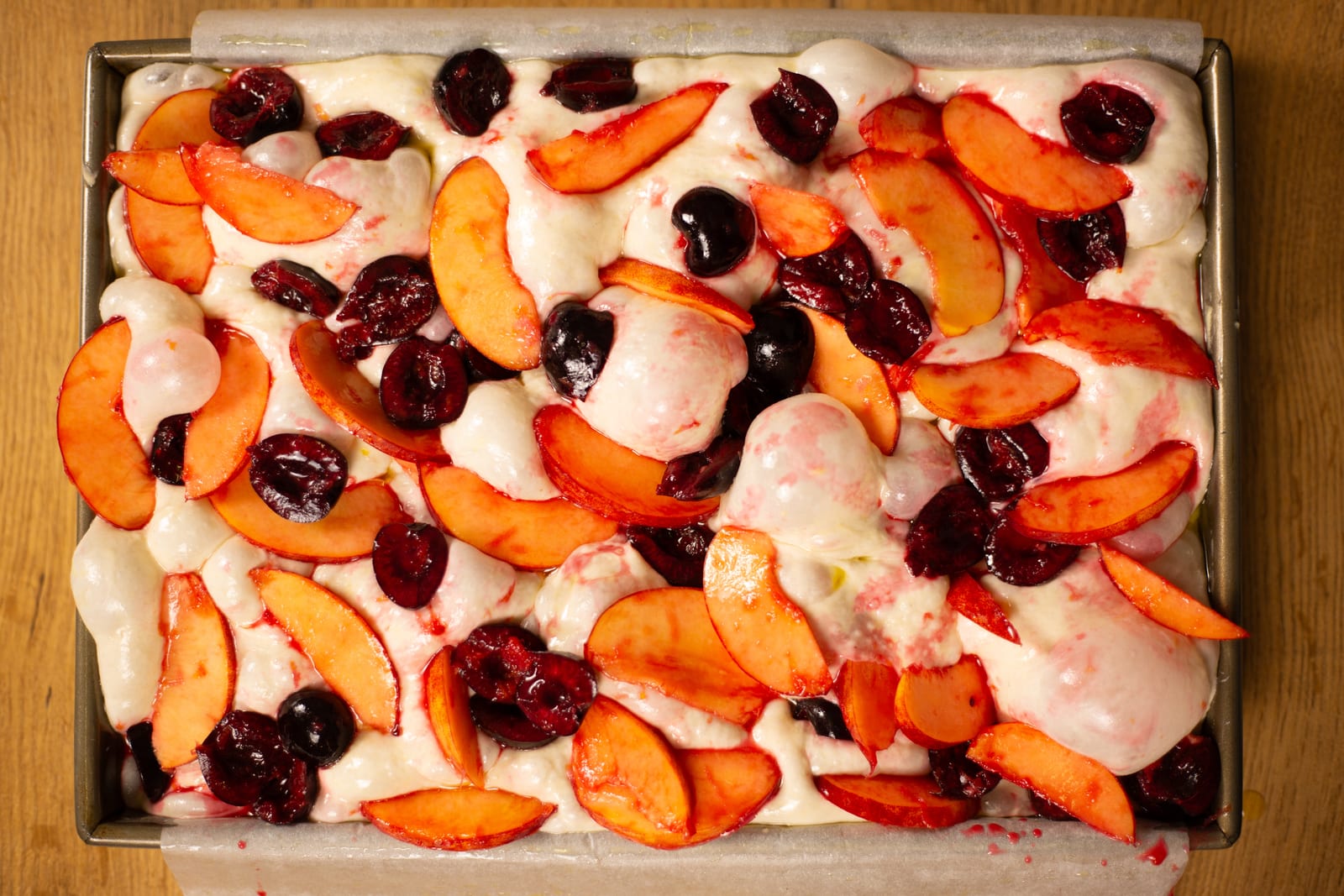 Focaccia dough topped with nectarine slices and cherries, before baking