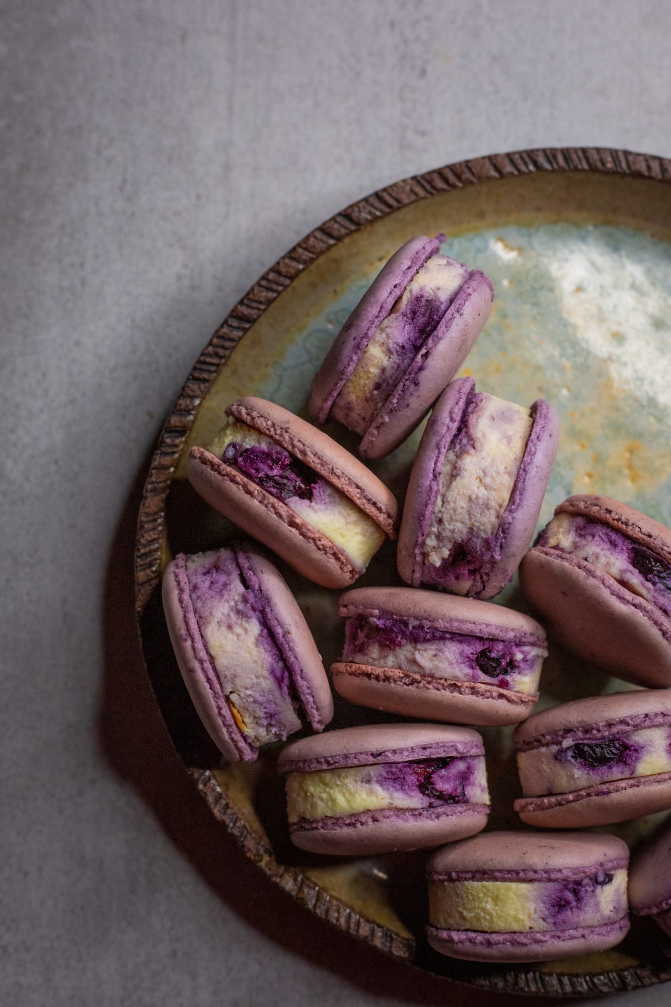 Close-up of a plate of blueberry cheesecake macarons, from above
