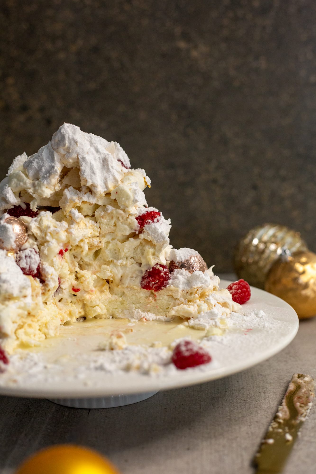 A Christmas tree pavlova broken up to serve, with raspberries