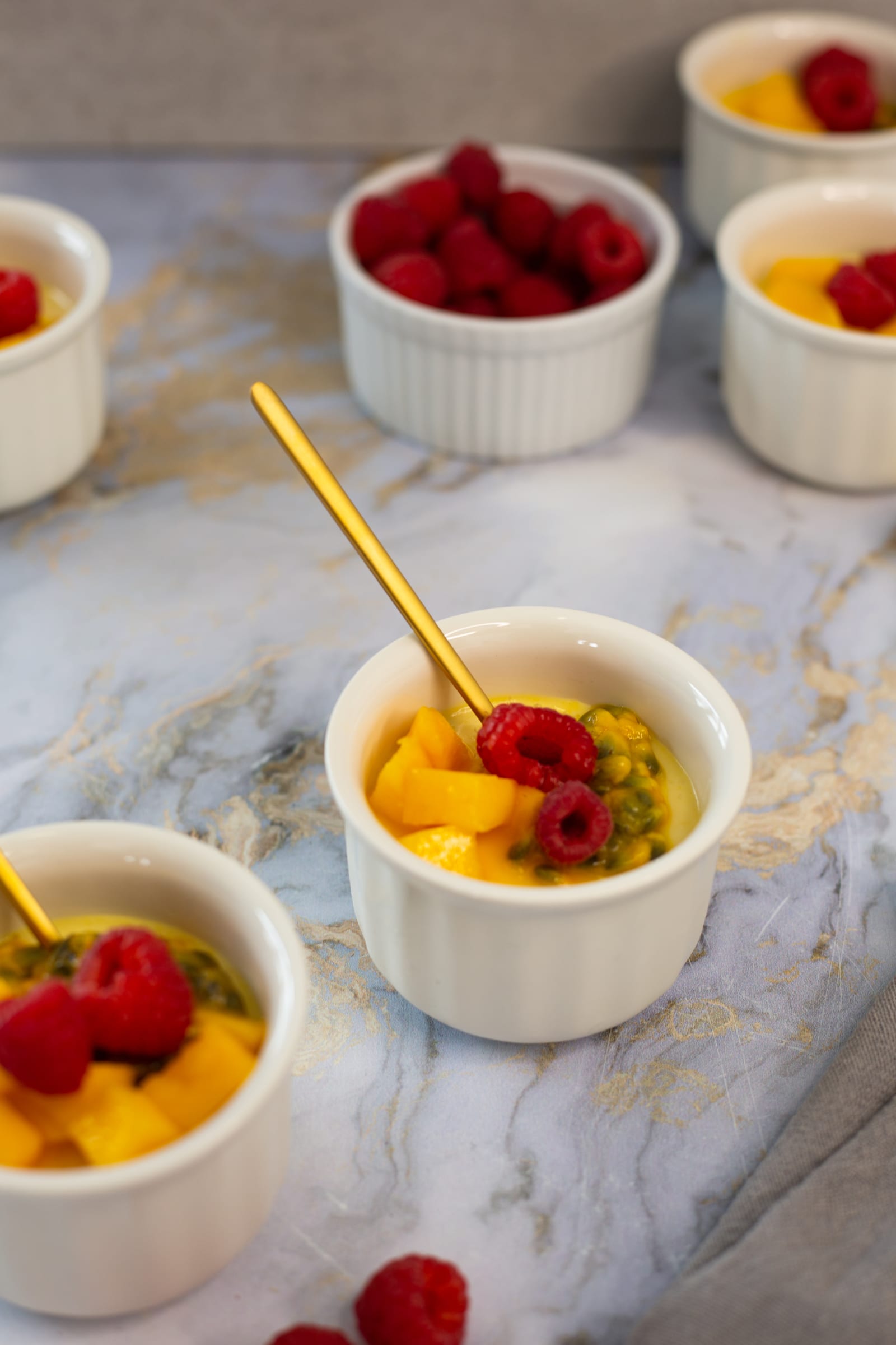 A gold spoon in a coconut, mango and granadilla baked yogurt, with the rest of the batch behind