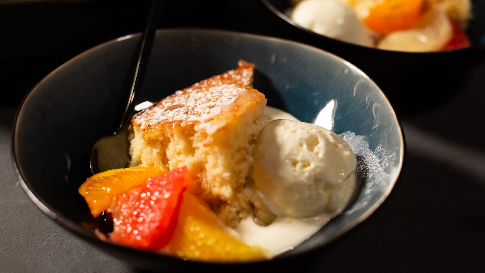 A bowl of citrus pudding with ice cream and fresh citrus