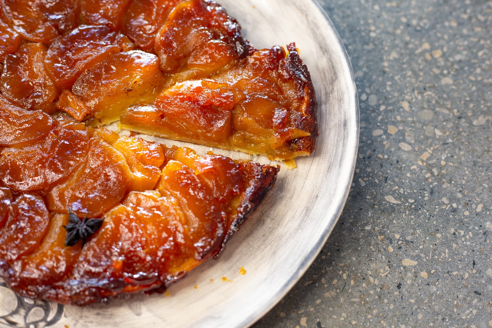 An apple tarte tatin with glossy caramel and a wedge pulled out